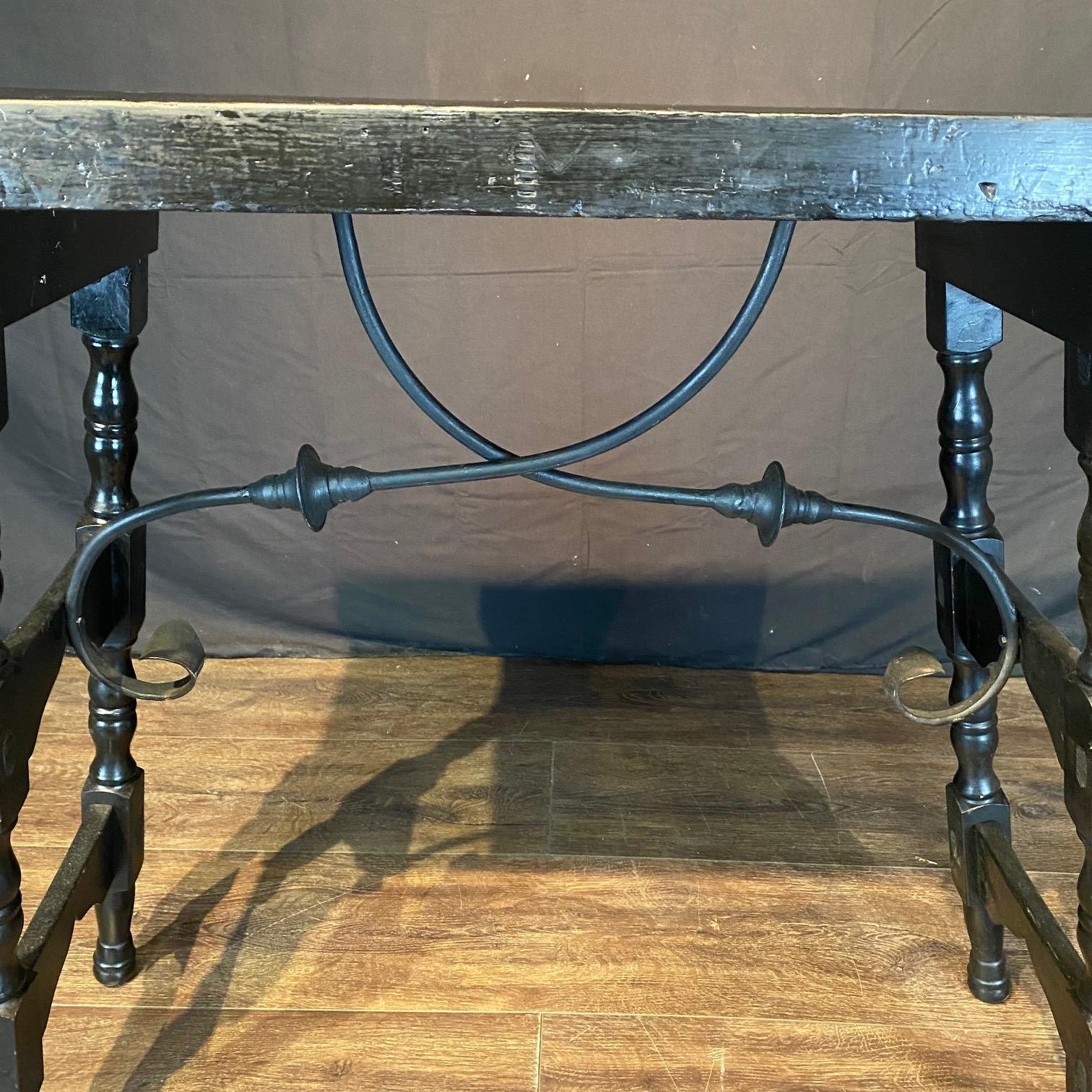 Spanish black side table or console table with hand made wrought-iron stretchers having a sturdy rectangular top sitting above an exquisite base made of splayed carved and turned legs connected to one another with a side stretcher, and each side is