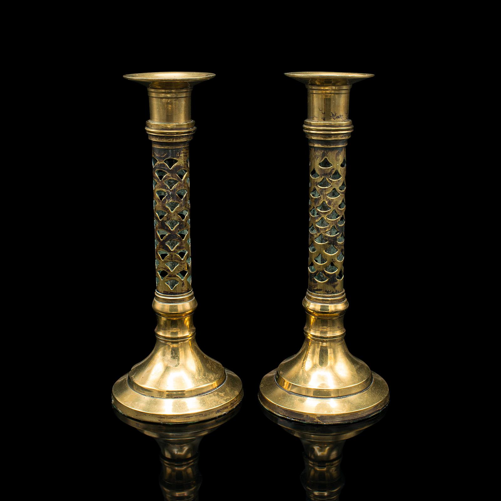 This is a pair of antique ecclesiastical candlesticks. An English, pierced brass candle holder in Aesthetic Period taste, dating to the Victorian period, circa 1890.

Distinguished candlesticks with an elegant appearance
Displaying a desirable aged
