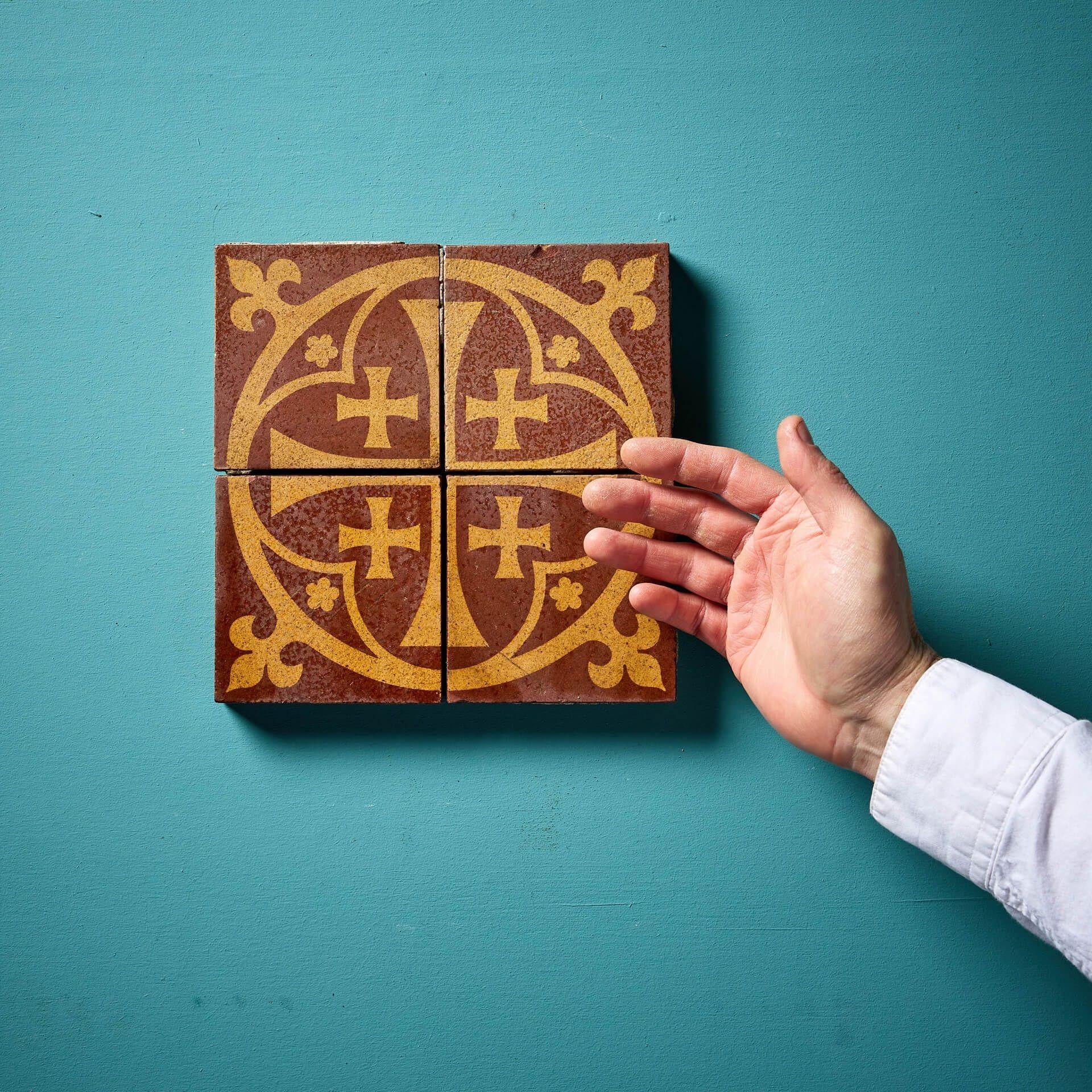 A set of four antique glazed encaustic 4 ¼ inch tiles (unmarked) together forming a decorative ecclesiastical tile panel depicting a cardinal moline cross within a quatrefoil with fleur de lys corners.

Dating from the mid 19th century, these