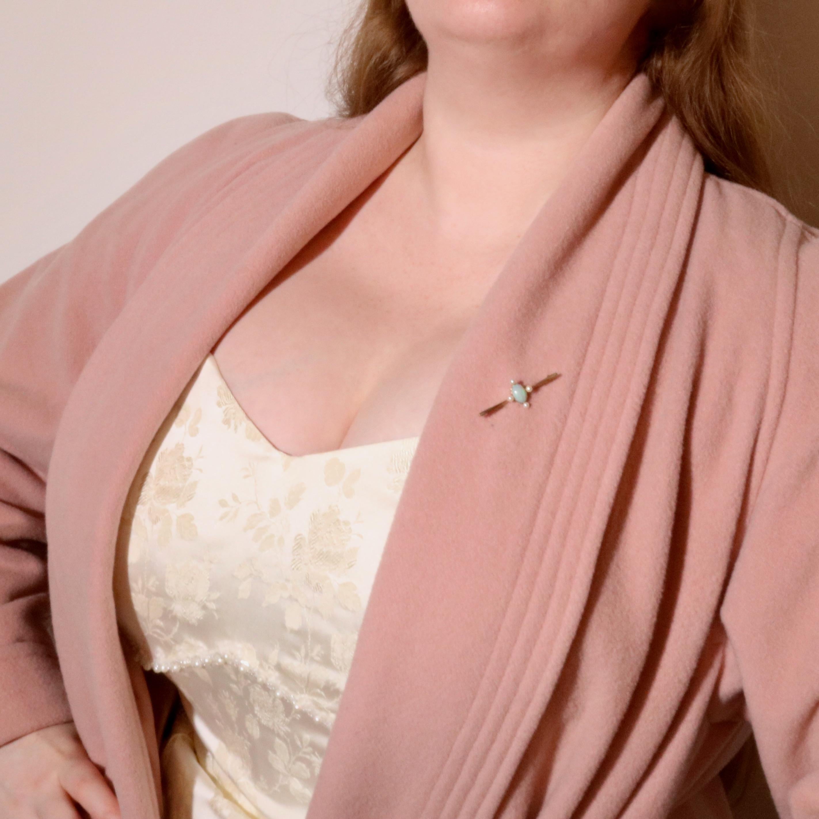 An Edwardian yellow gold, opal, and pearl brooch, comprising an oval opal cabochon, and 4 seed pearls, set in 15 karat yellow gold, with 15 karat yellow gold pin and fittings.  

This striking Edwardian brooch is set to the centre with an ethereal