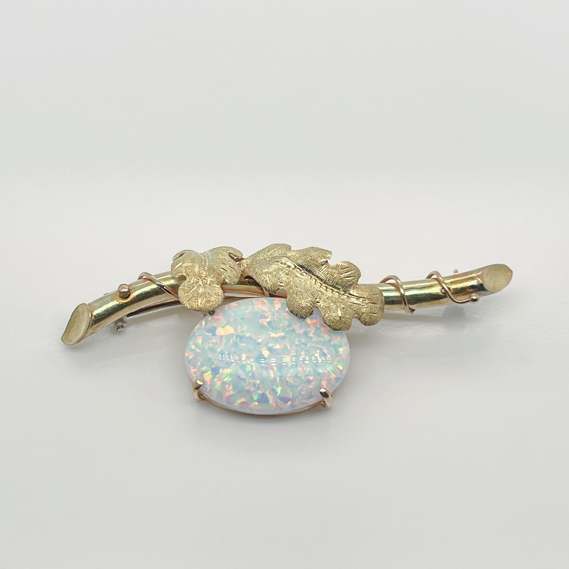 A very fine Edwardian style brooch. 

Prong set with a large reconstituted opal cabochon under an bar in the form of a branch that is wrapped with a vine with engraved and textured leaves.

Simply a wonderful brooch!

Date:
20th Century

Overall