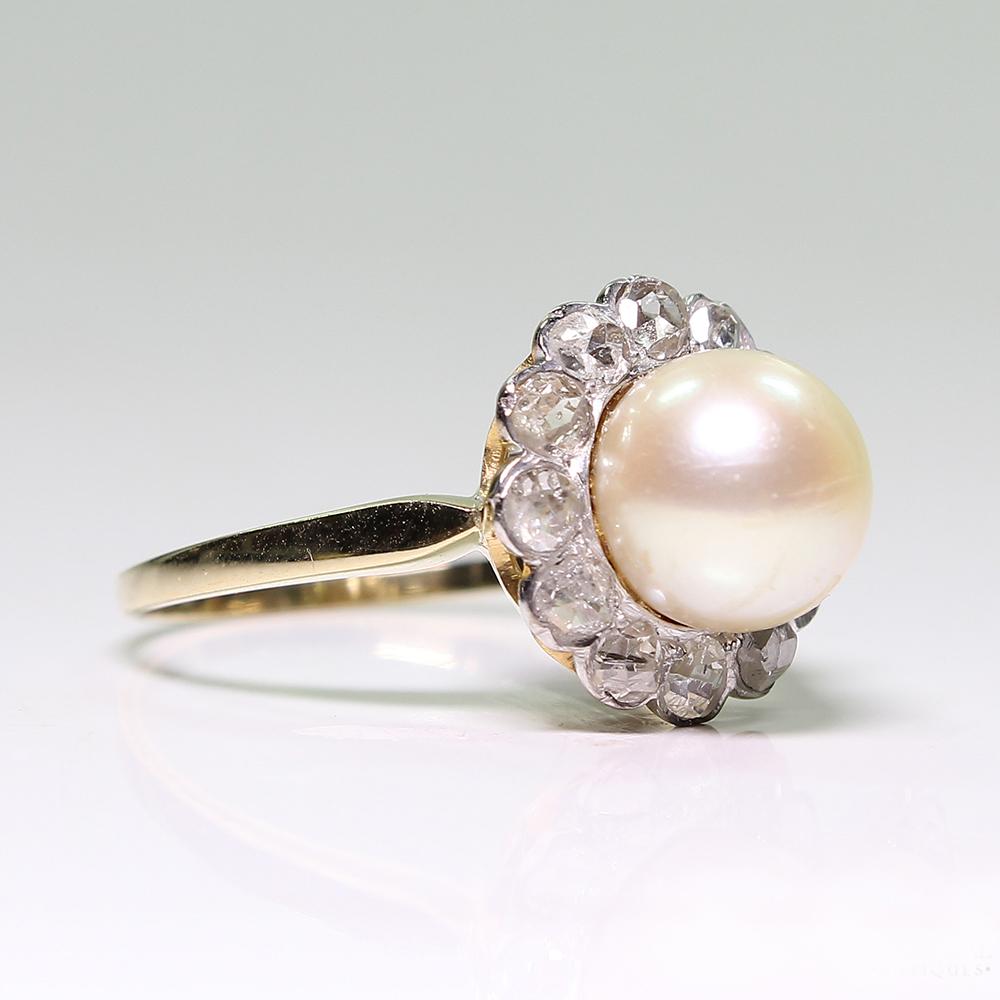 Period: Edwardian (1901-1920)
Composition: 18K gold and Platinum.

Stones:

•	1 cultured pearl that measures 8mm.
•	12 Rose cut diamonds of H-SI1 quality that weigh 0.75ctw.
Ring size: 7   
Ring face:  13mm in diameter. 
Rise above finger: