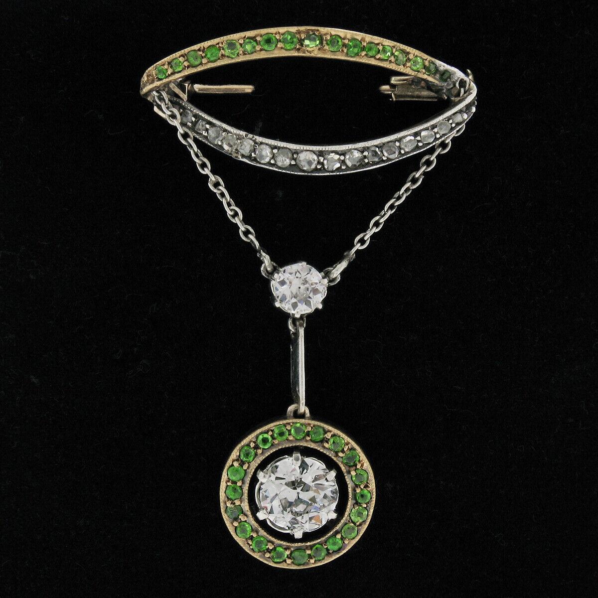Here we have a very fine antique diamond and demantoid garnet dangle pin brooch crafted in solid 18k yellow gold during the early 1900's. It features a large, GIA certified 1.17 carats, old European cut diamond which is prong set at the center of