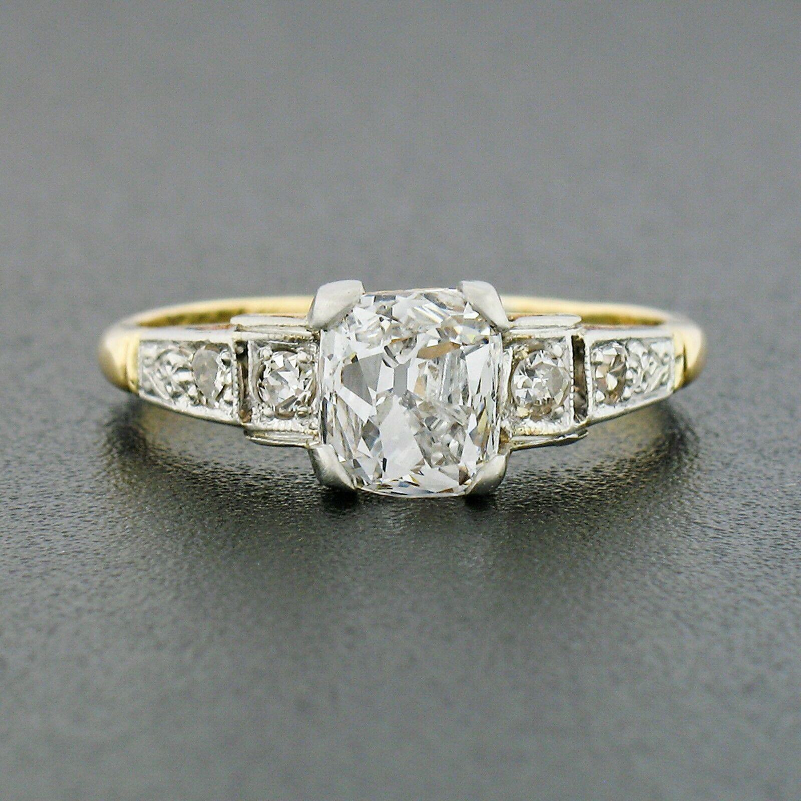 This breathtaking antique diamond engagement ring was crafted from solid 18k yellow gold with platinum top during the Edwardian era. It features a gorgeous, old mine cut diamond solitaire at its center with a rare cushion shape. The diamond is GIA