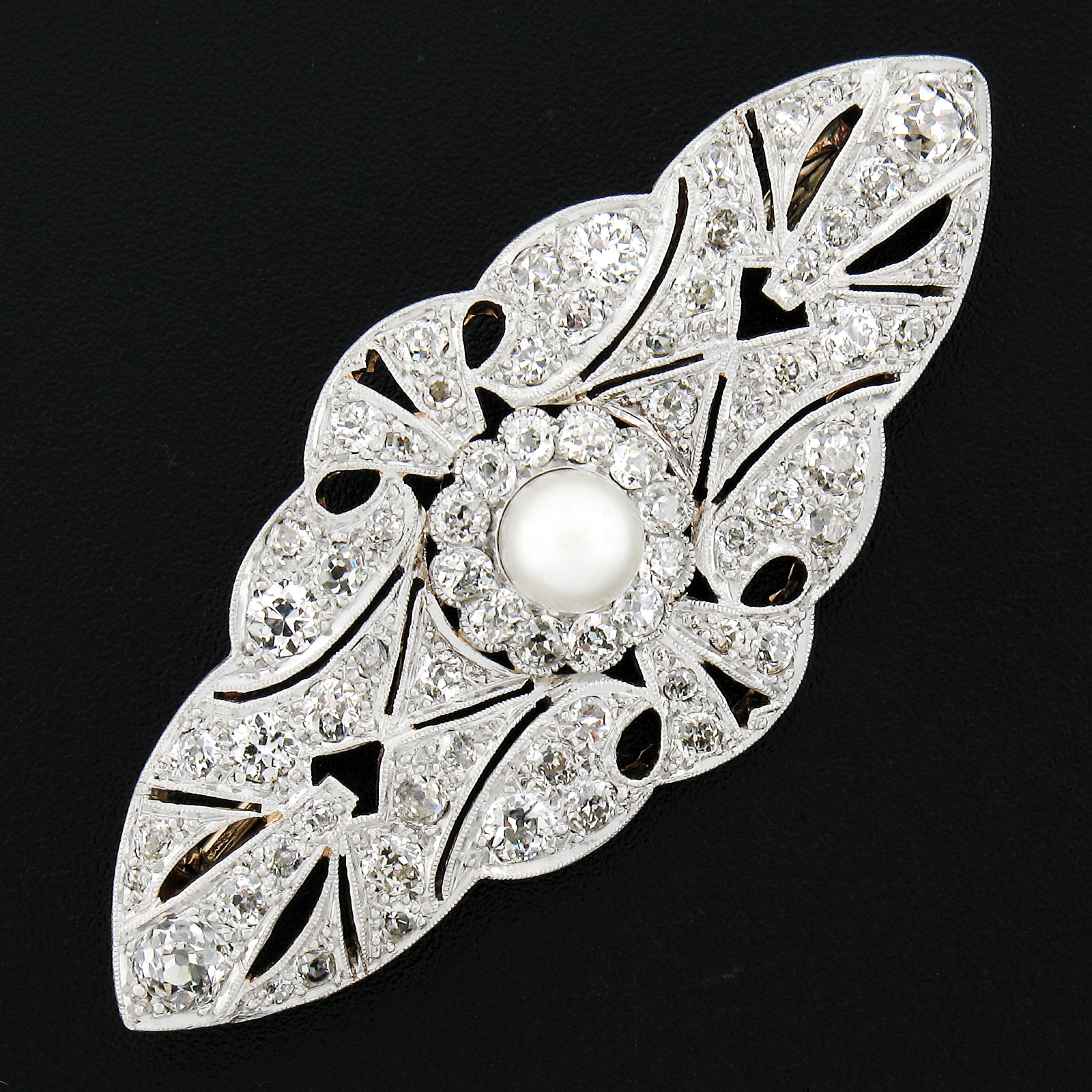 This well preserved and jaw dropping antique pin brooch is crafted during the Edwardian era from solid 18k yellow gold and platinum top. At the center of the brooch a singular round bead pearl stands out with its mesmerizing white color and is