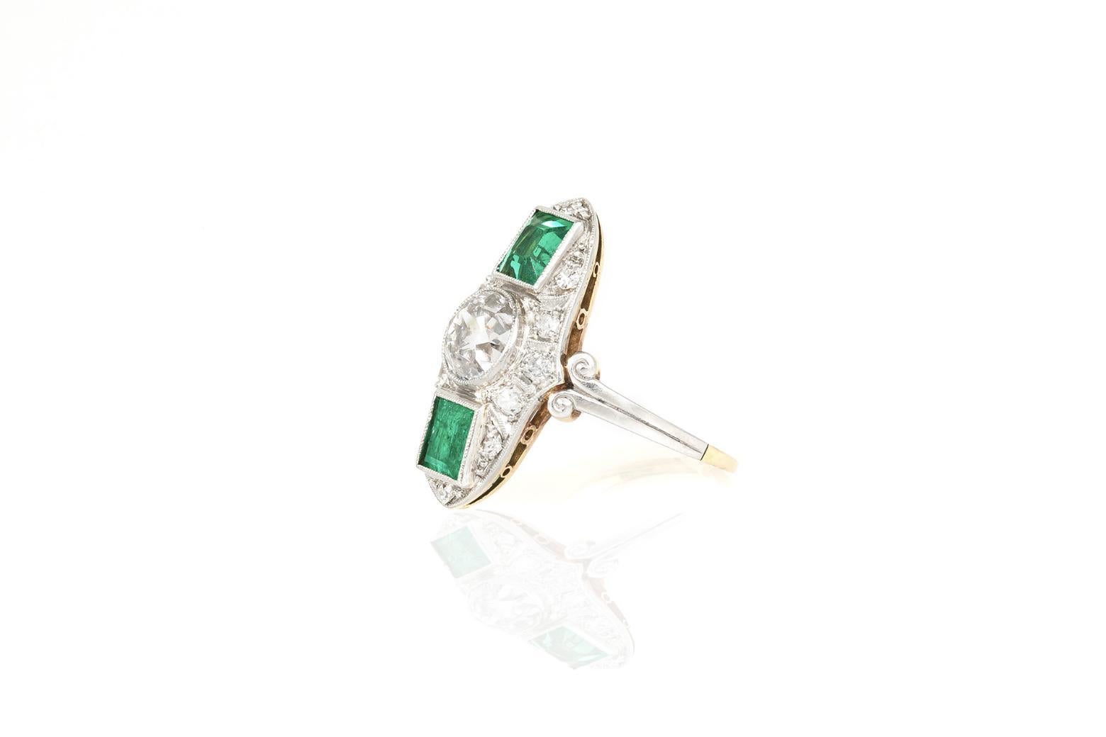 Finement réalisée en platine et en or jaune 18 carats avec un diamant de taille européenne pesant environ 1,50 carat et deux émeraudes de taille carrée pesant environ 1,00 carat au total. La bague est ornée de petits diamants à taille unique pesant