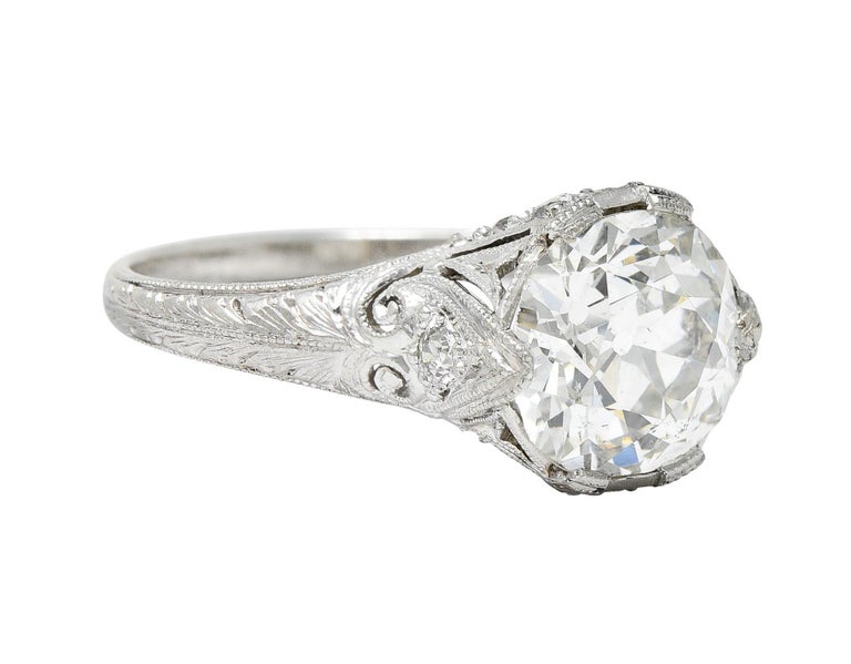Centering an old mine cut diamond weighing approximately 2.08 carats - J color with SI2 clarity

Set within stylized wide prongs and a ribbon-like head accented by milgrain edges

With pierced heart motif at shoulder terminating as engraved