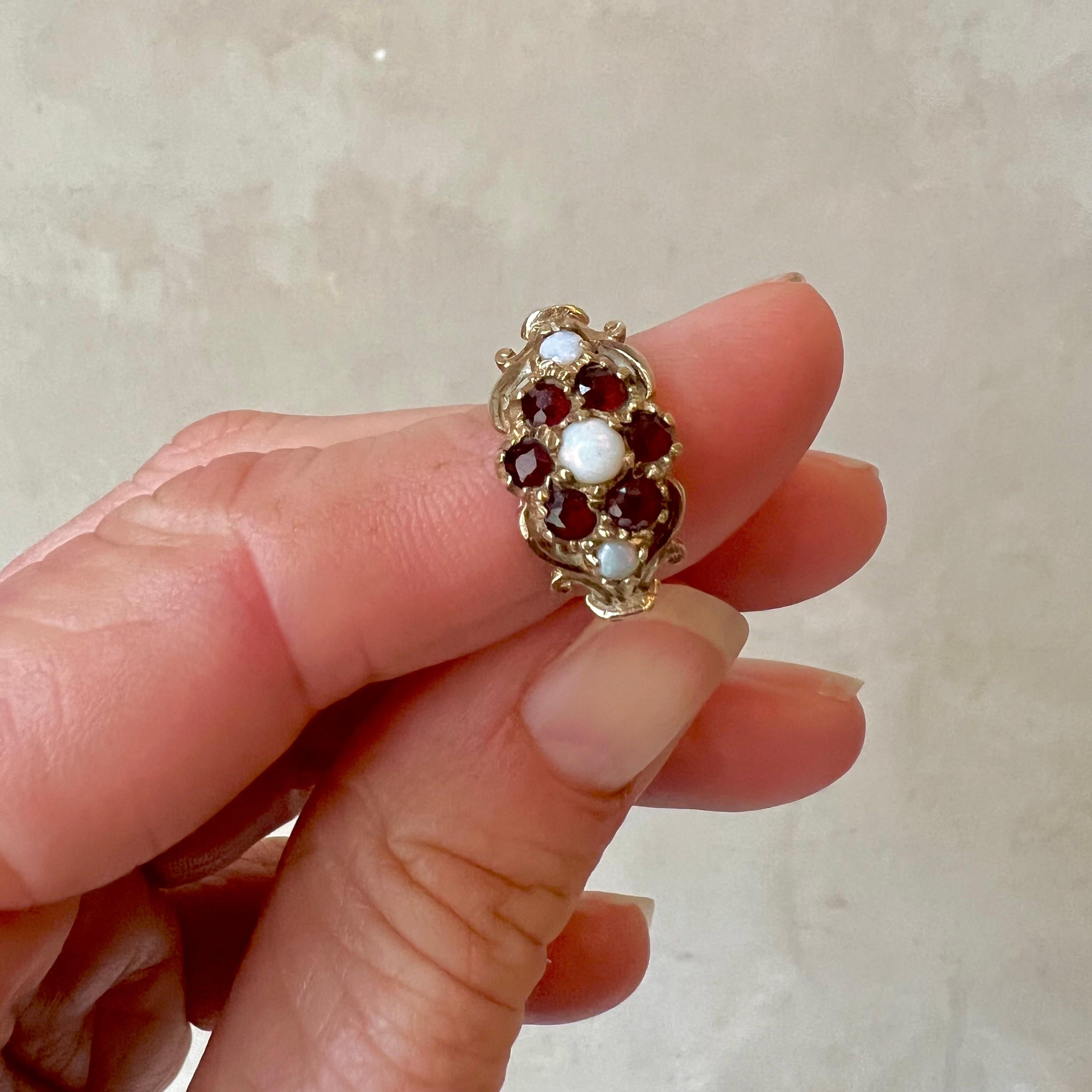 Step into the allure of history with this antique Edwardian 9 karat yellow gold halo ring, hailing from England. Adorned with the mesmerizing hues of opal and the deep richness of garnet, this ring is a testament to timeless beauty and sophisticated