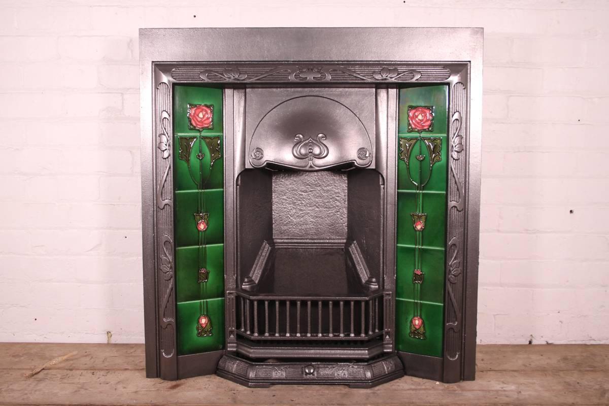 A good example of an antique Edwardian Art Nouveau cast iron grate, circa 1905.
Complete with a set of original tube lined Art Nouveau fireplace tiles.

This grate has been finished the traditional black grate polish, leaving a gun metal / pewter