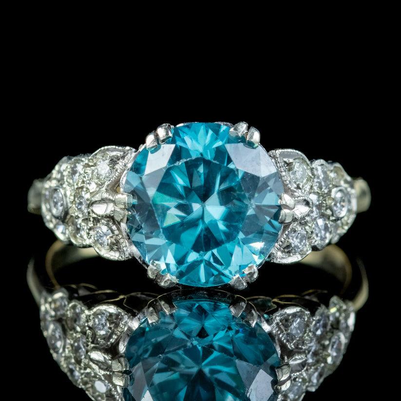 A stunning antique Edwardian ring adorned with a beautiful blue zircon solitaire weighing approx. 3.6ct. The centre stone is mounted in a platinum gallery with ornate, diamond encrusted shoulders down each side (approx.  0.40ct total) leading into a