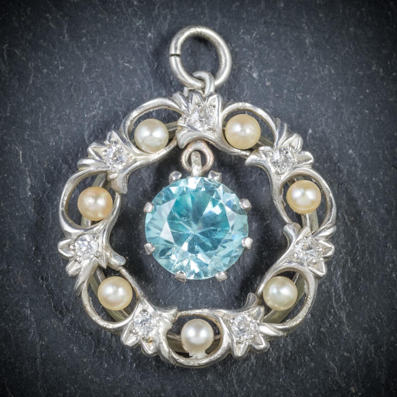 This beautiful antique Blue Zircon pendant is Edwardian, Circa 1915

Adorned with a lovely Blue Zircon hanging in the centre with a wreath of Pearls and old cut Diamonds surrounding it that are SI 1 - H Colour 

Set in a Platinum gallery and backed