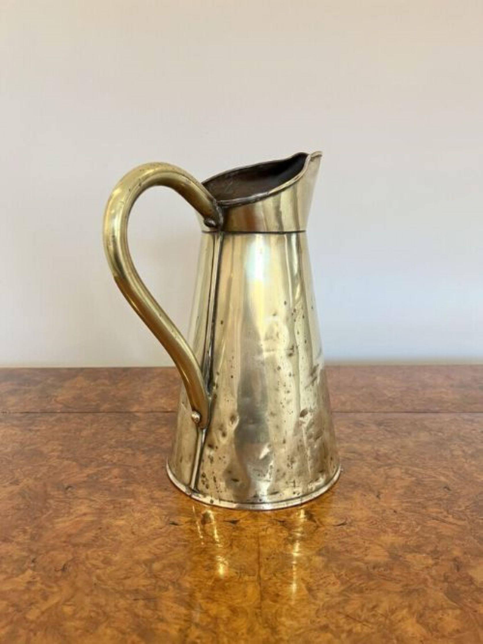 Antique Edwardian brass jug having an antique Edwardian brass jug with a shaped handle to the back.