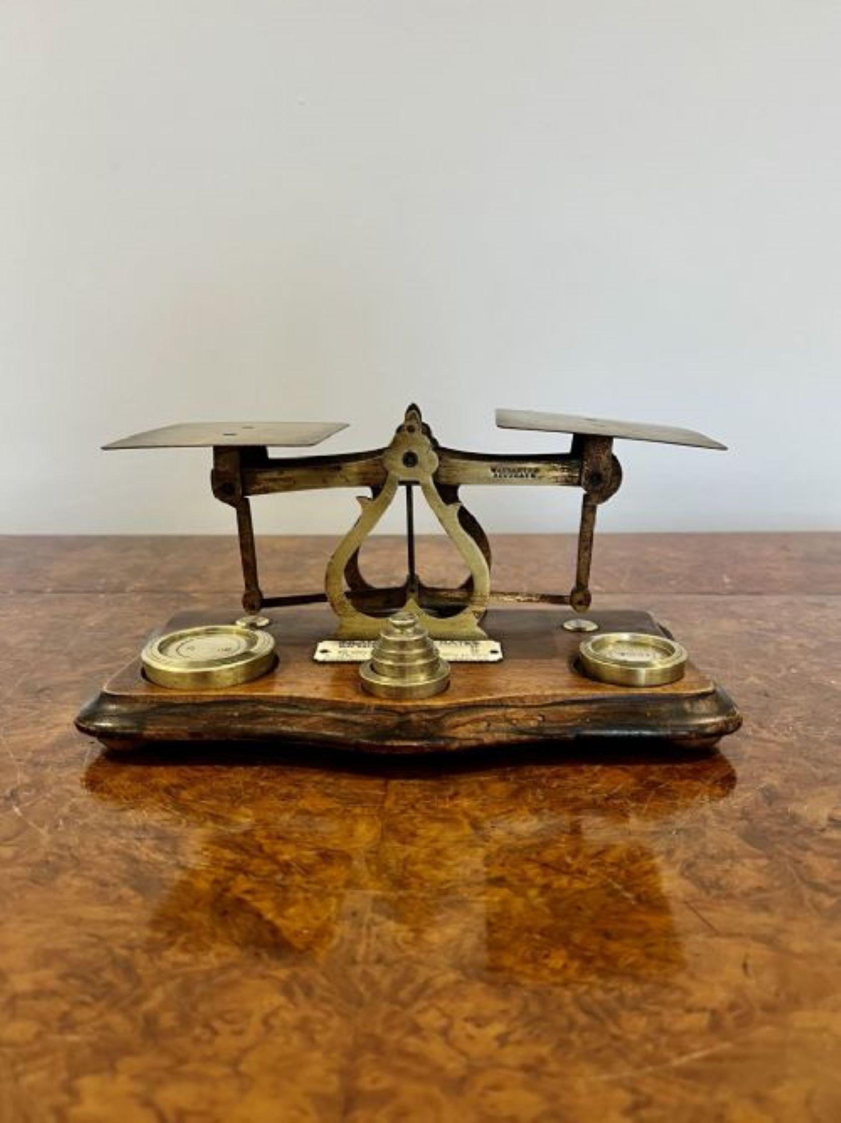 Antique Edwardian brass postal scales having a pair of original brass postal scales standing on a hardwood stand with the original brass weights 