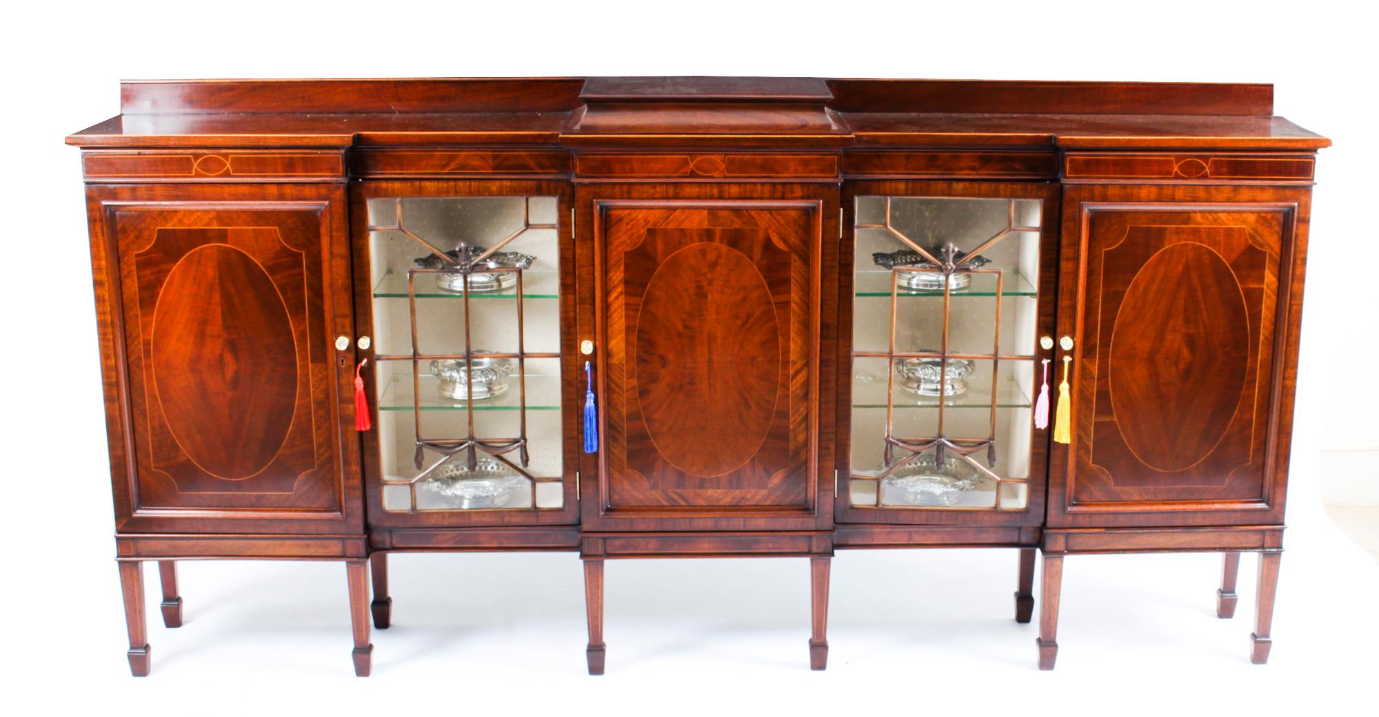 This is a stunning antique Edwardian flame mahogany boxwood strung breakfront sideboard, circa 1900 in date

The double breakfront rectangular top over three oval panel cupboards and two astragal glazed doors, and raised on square tapering legs