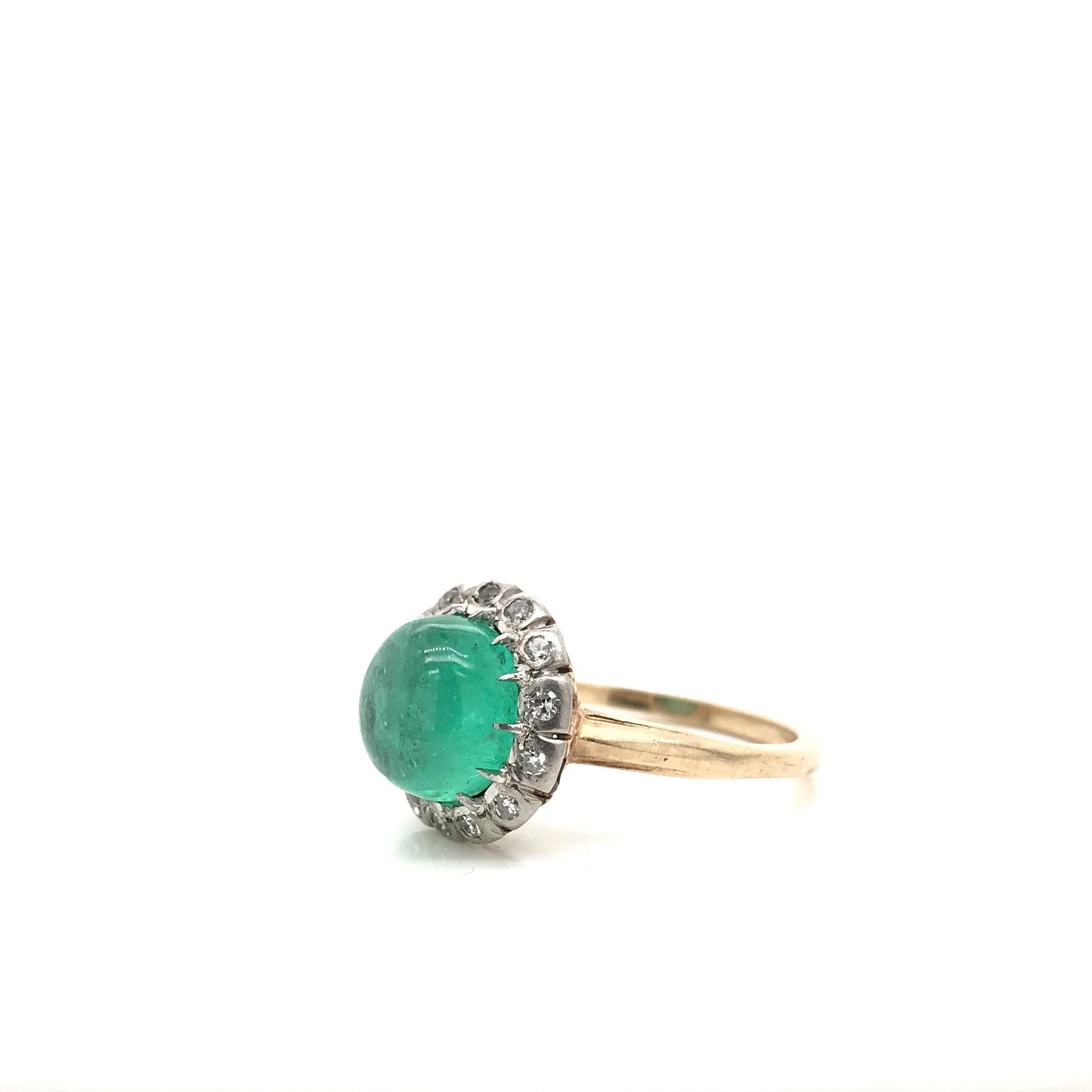 This stunning antique piece was crafted sometime during the Edwardian design period (1900-1920). The 14K gold setting features a center cabochon cut emerald measuring approximately 3 carats. Cabochon cut gemstones are unfaceted, their hue generously