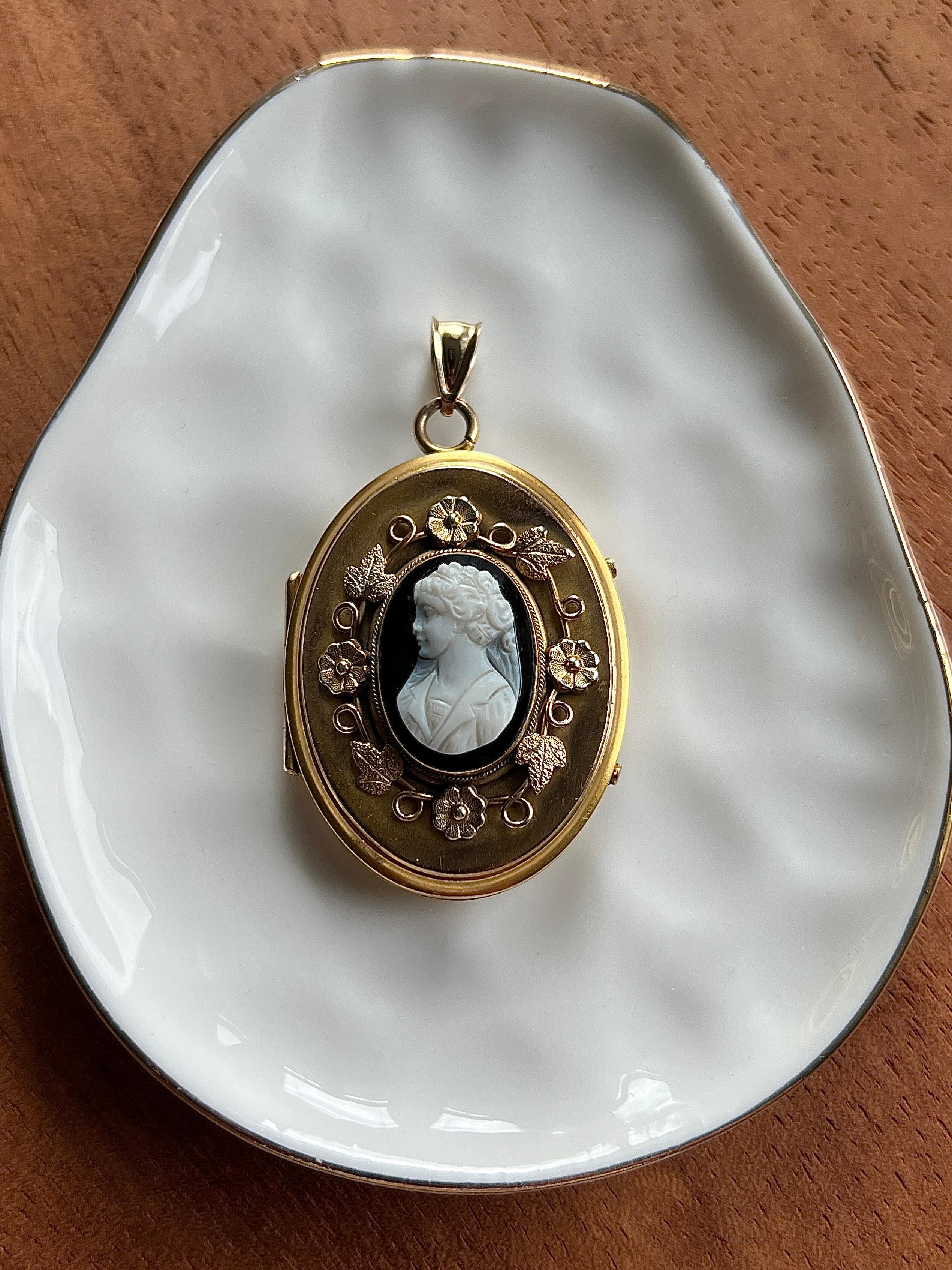  This captivating locket from the 1900s showcases the refined artistry of the Edwardian era through its beautifully carved agate cameo depicting a classical female profile. Crafted in 10 karat yellow gold, the substantial piece measures 1.5 inches