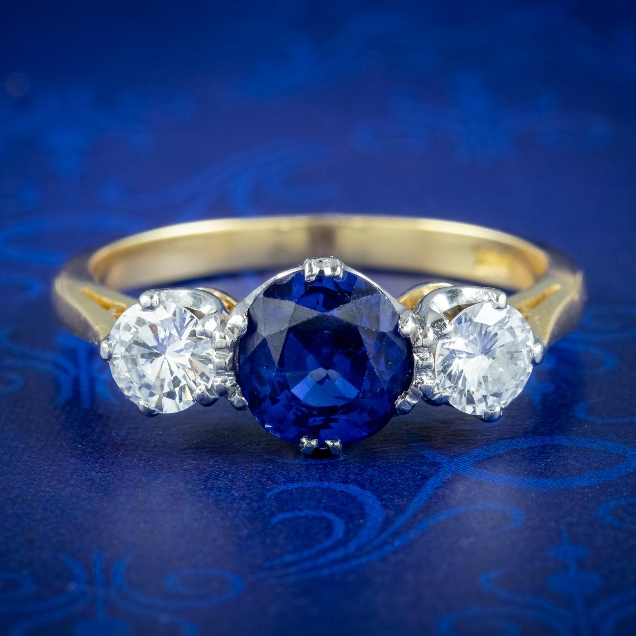 A stunning antique Edwardian trilogy ring crowned with a natural blue Ceylon sapphire flanked by two bright brilliant cut diamonds. It’s accompanied by two comprehensive gem reports which suggest the sapphire weighs between 1.45 - 1.53ct and is of