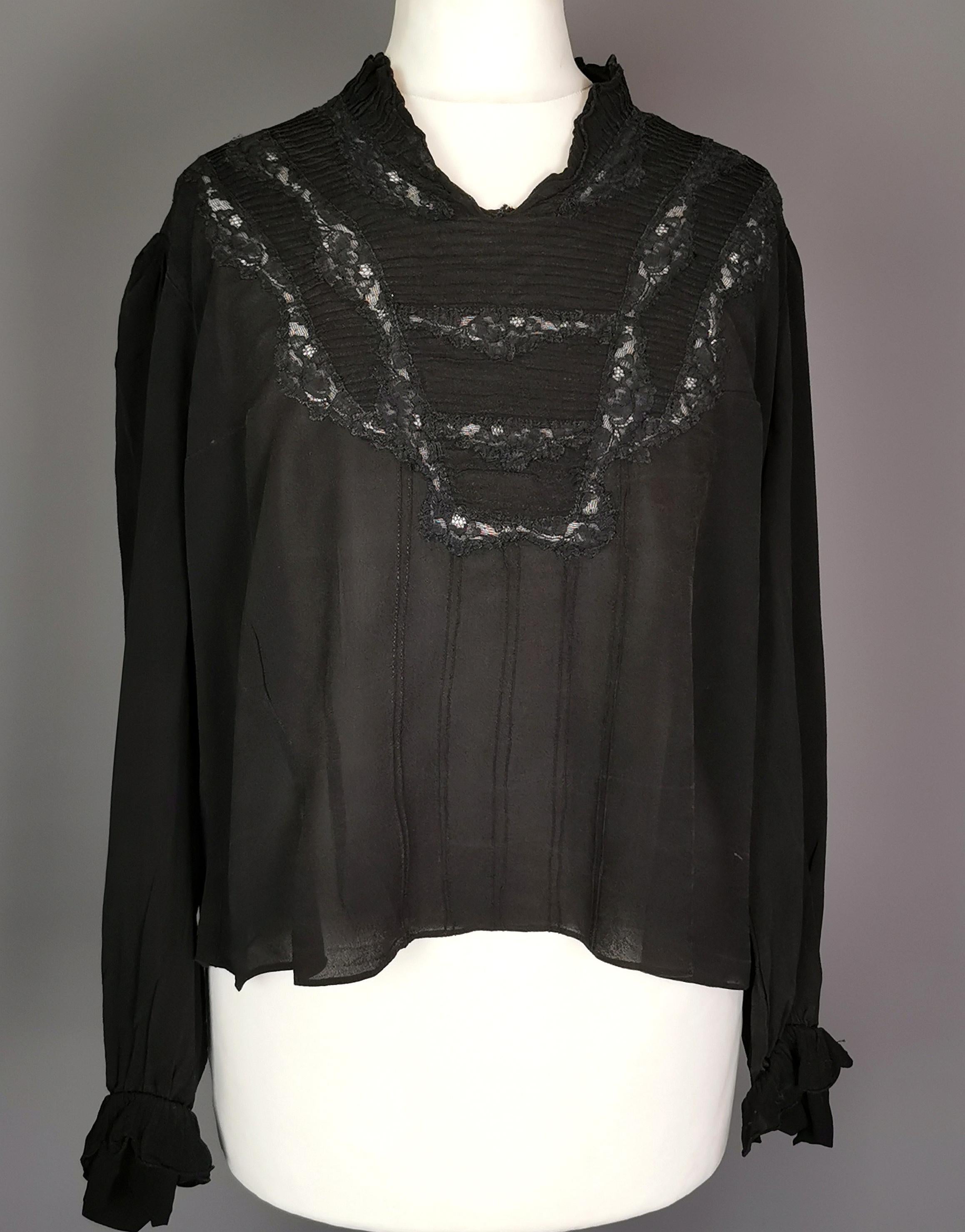 A stunning late Edwardian era black chiffon blouse.

It has a pretty cut out lace covered pattern to the front of the dress with darts down the front and pleat detailing.

The blouse has long sleeves with silk button ruffle cuffs.

The collar is
