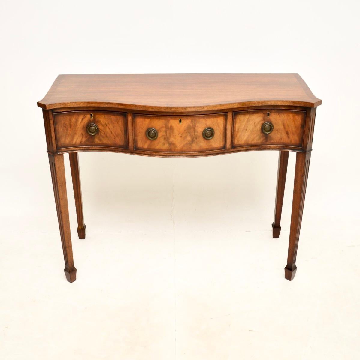 A lovely antique Edwardian console side table, made in England and dating from the 1900-1910 period.

This is of superb quality and is a great size, with some lovely design features. It has a serpentine shaped front and stands on tapered legs