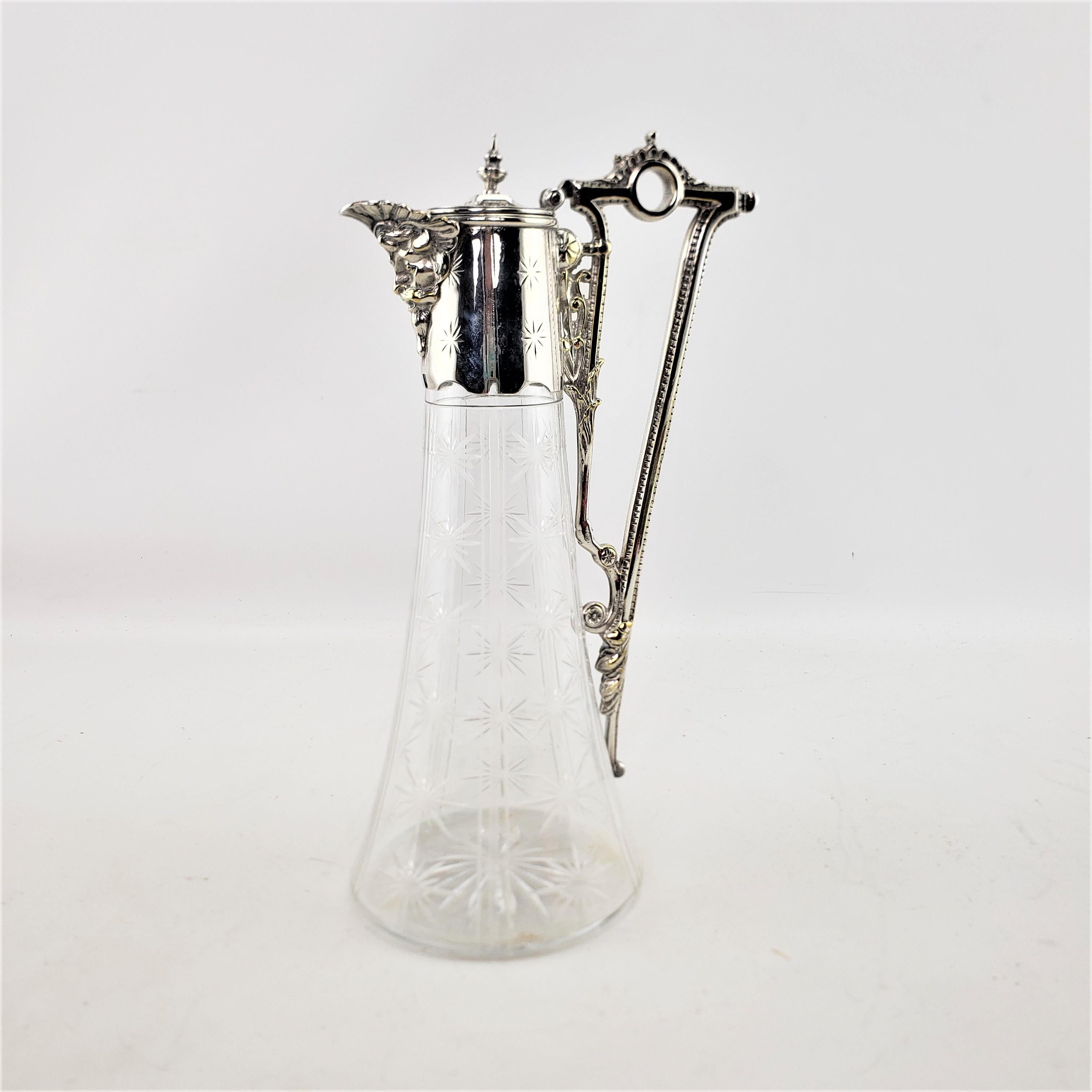 This antique cut crystal and silver plate mounted claret jug is unsigned, but presumed to have originated from England and dates to approximately 1900 and done in the period Edwardian style. The claret jug is done with a tapered cut crystal base