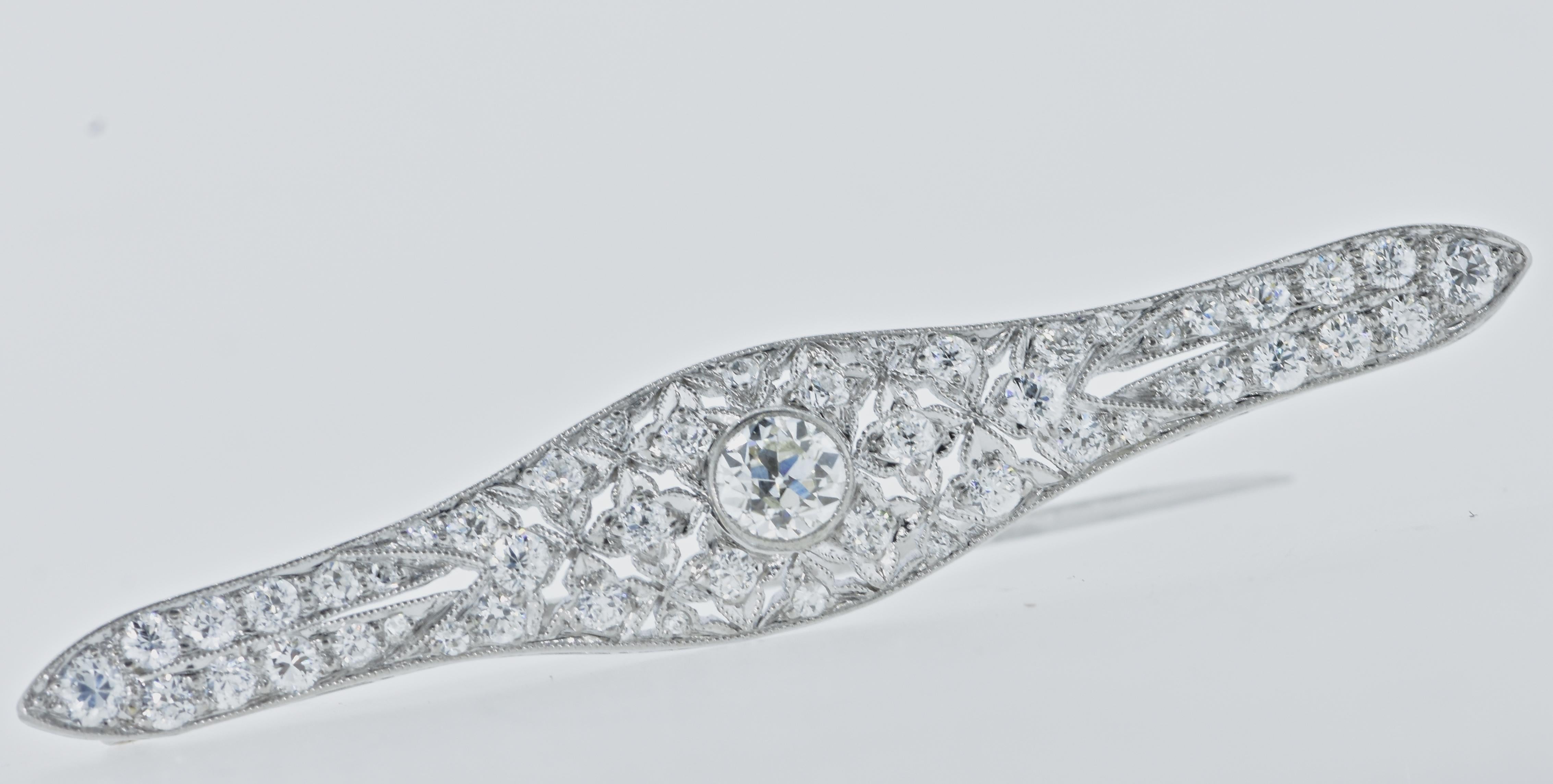 Edwardian platinum and diamond antique pin in fine condition and displaying wonderful Edwardian filigree work with fine milgrained edges.  The center diamond is estimated to weigh .37 cts., and the total diamond weight is 1.42 cts.  All of the