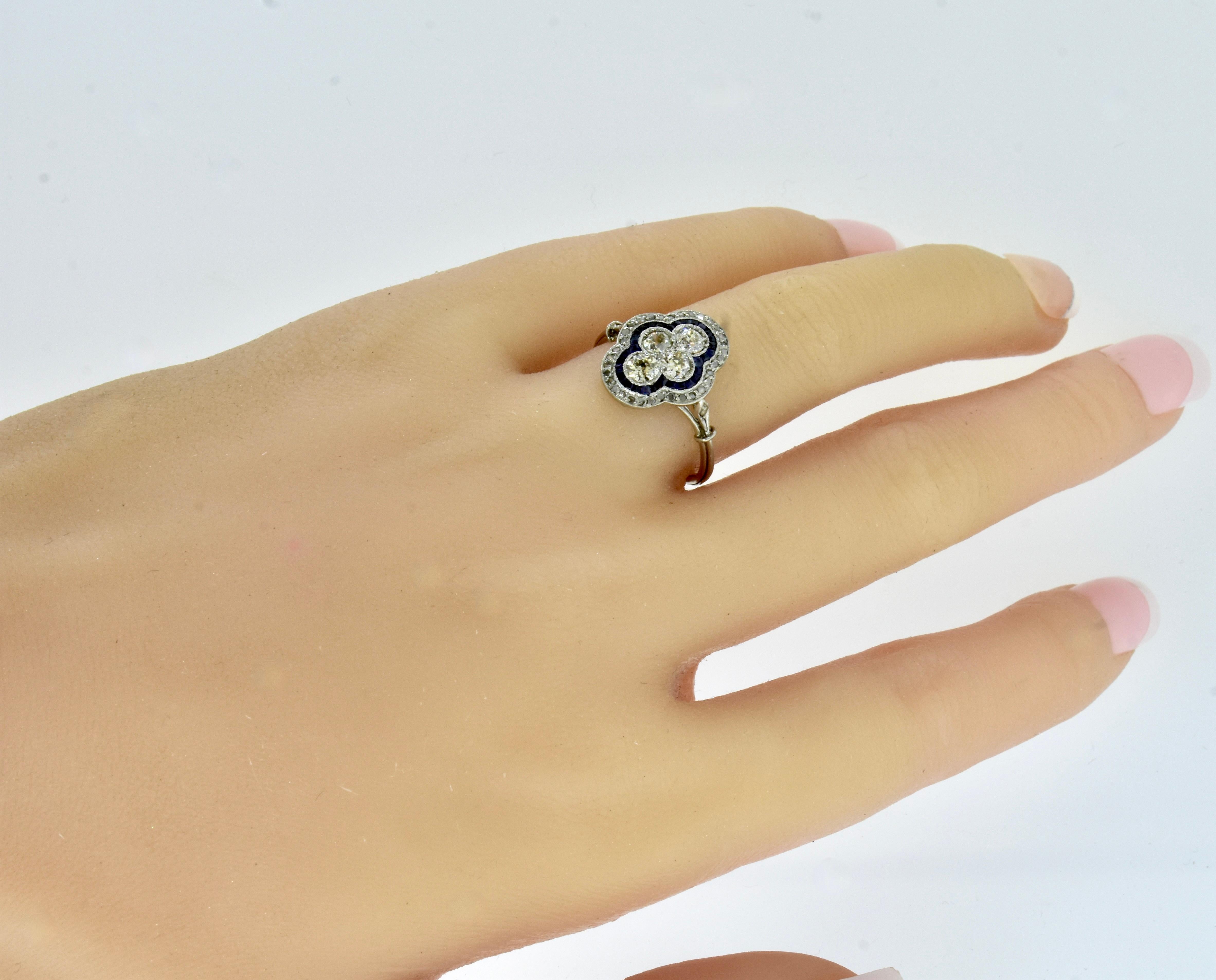 Antique Edwardian diamond and fancy cut natural vivid blue sapphire platinum ring in a quatrefoil motif, circa 1915. The center four diamonds are surrounded by calibre cut natural vivid blue sapphires which are then  surrounded by rose cut diamonds