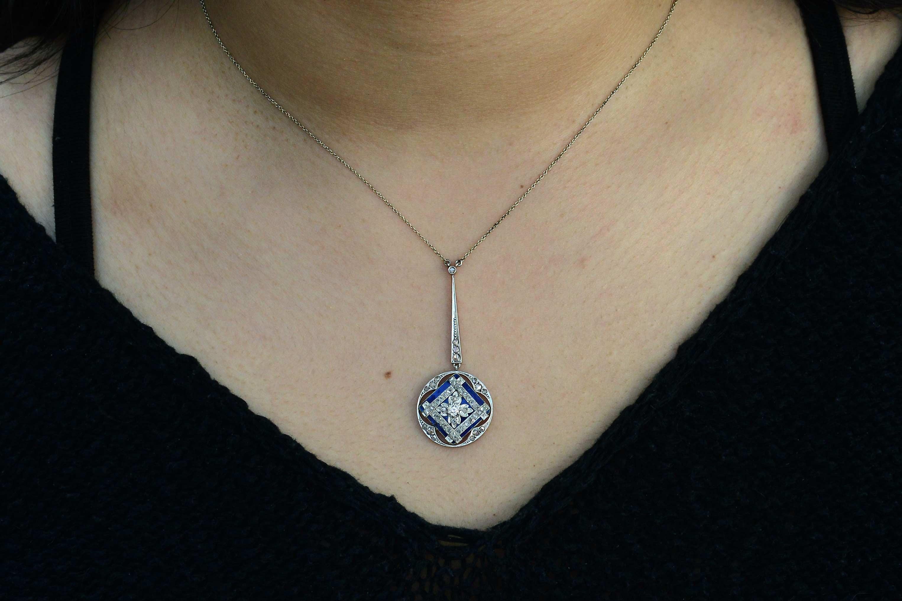 A stunning antique, this lavalier style necklace is eminently wearable. With a velvety blue enamel serving as the canvas for the 40 rose cut diamonds set in an interesting lattice pattern. The drop style filigree pendant dangles from a single,