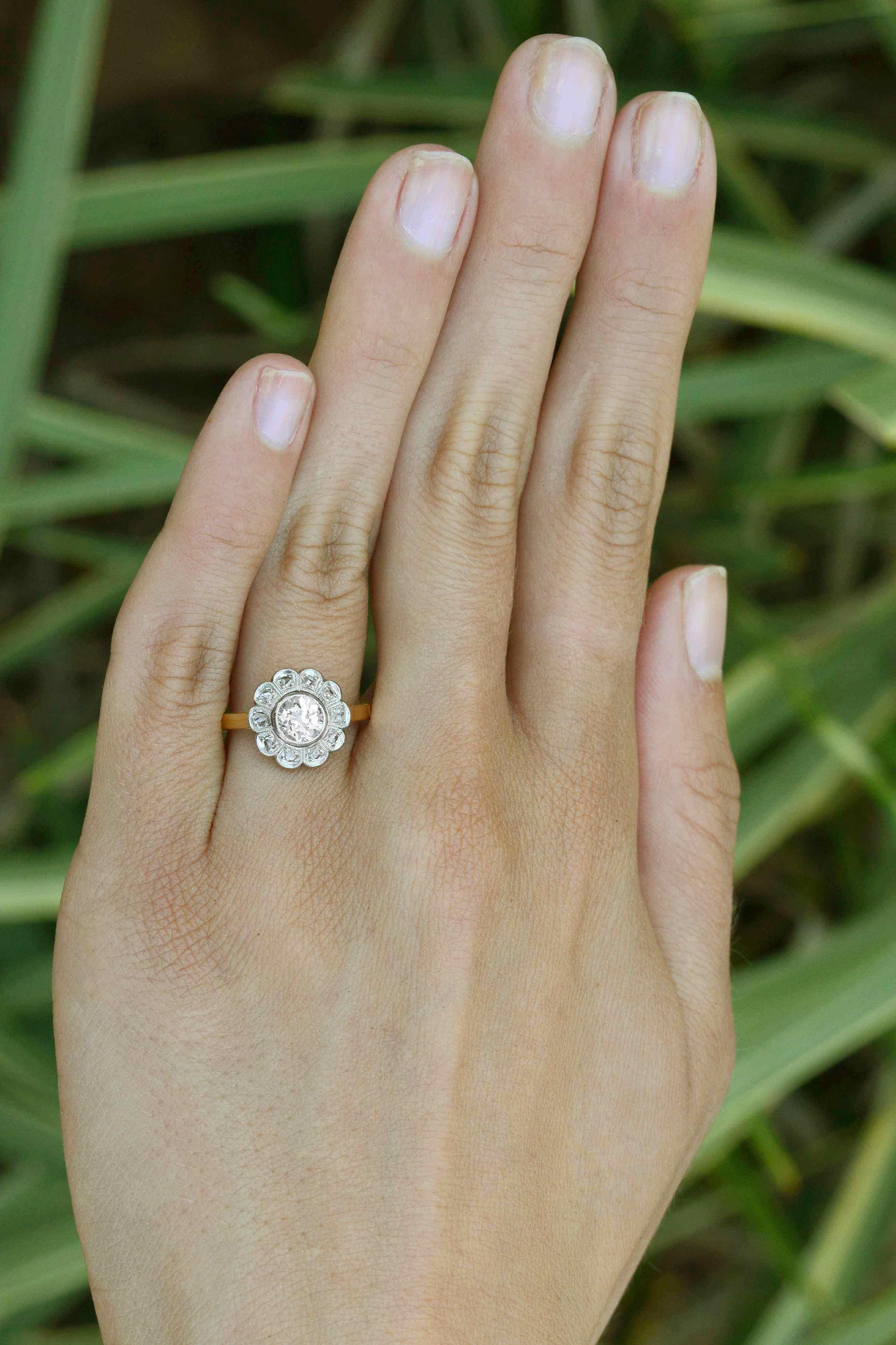 Der antike edwardianische 1-Karat-Diamant-Verlobungsring Oakland ist ein reizvoller Blumenschmuck aus den frühen 1900er Jahren. Im Mittelpunkt steht ein fesselnder Brillant im alten europäischen Schliff:: der von einem Halo aus Diamanten im