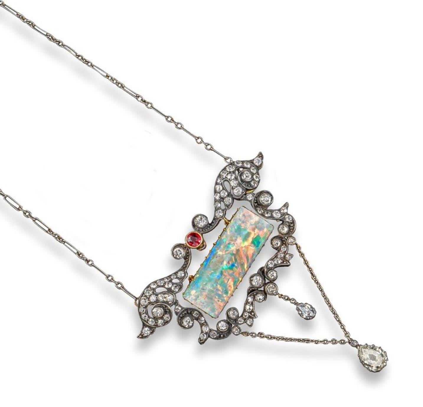 A very fine Belle Époque opal, diamond and ruby lavalier pendant. Set with old circular-cut diamonds throughout and in the centre with a rectangular opal plaque surmounted with a circular-cut ruby. The mount, designed as a series of interconnected