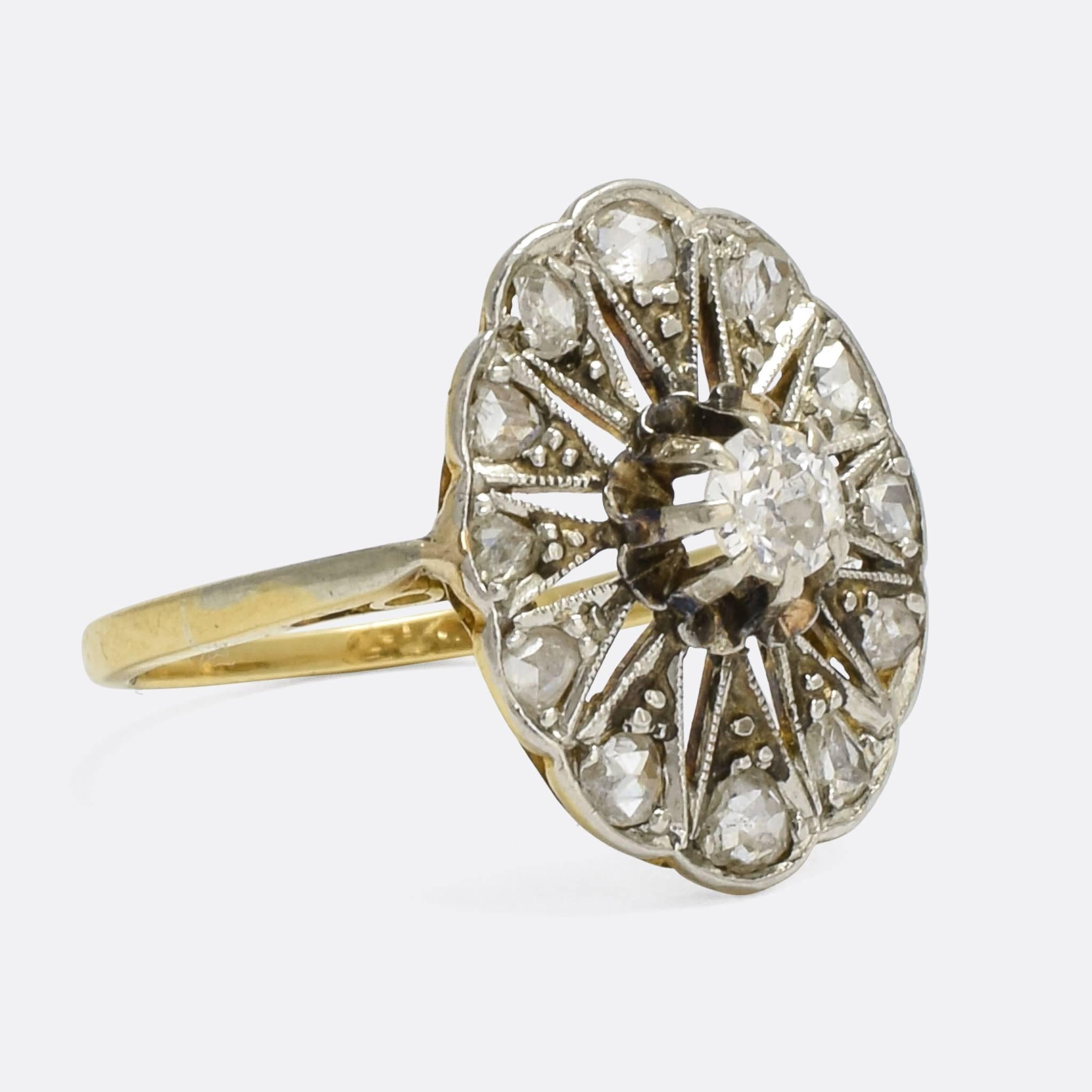 An unusual Edwardian diamond ring. The central old Euro stone is set in a scalloped claw mount, and surrounded by an oval cluster of rose cut diamonds, with an openworked star motif and finished in millegrain. It dates from c.1910, modelled in