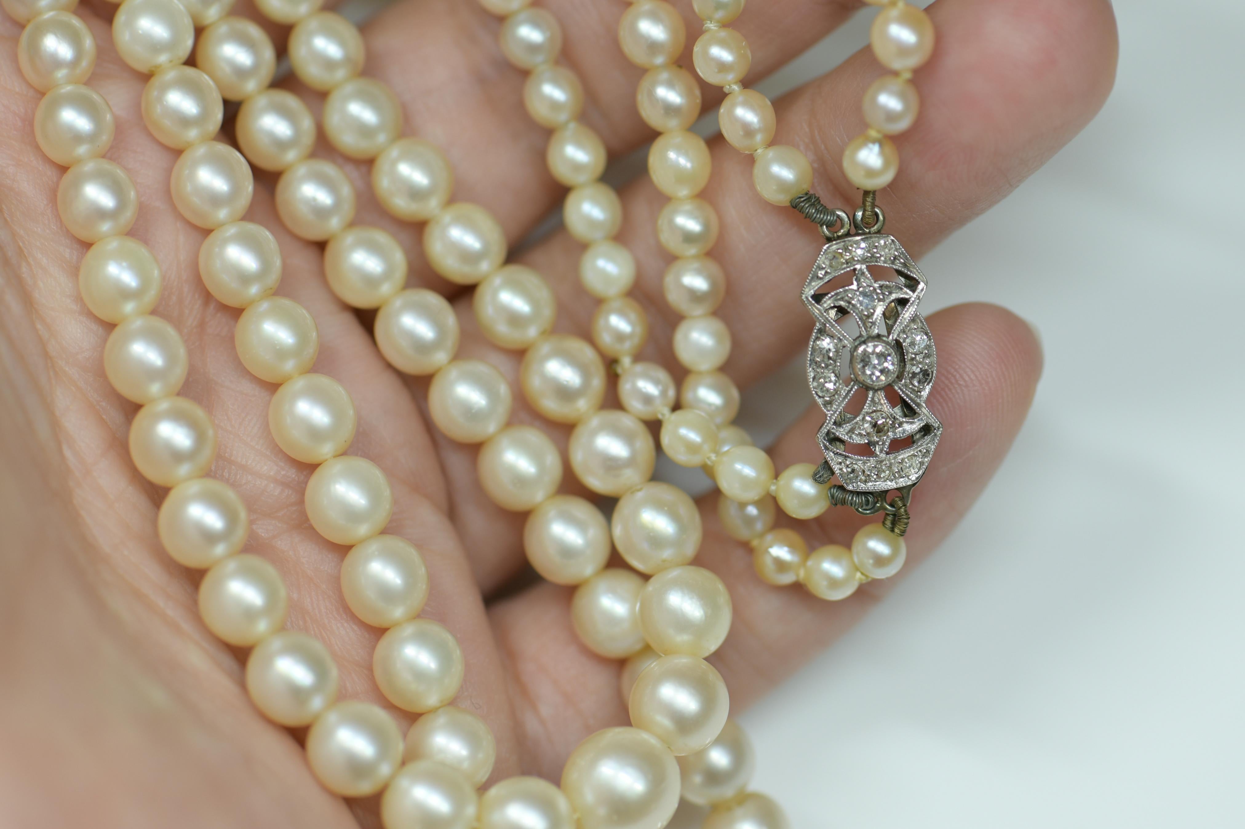 This beautiful necklace of lustrous white pearls dates from circa 1910. Lustrous graduated double white, creamy, dreamy cultured pearls culminate in a scintillating constellation of bright white and round diamonds in this elegant. Clasp measures 18