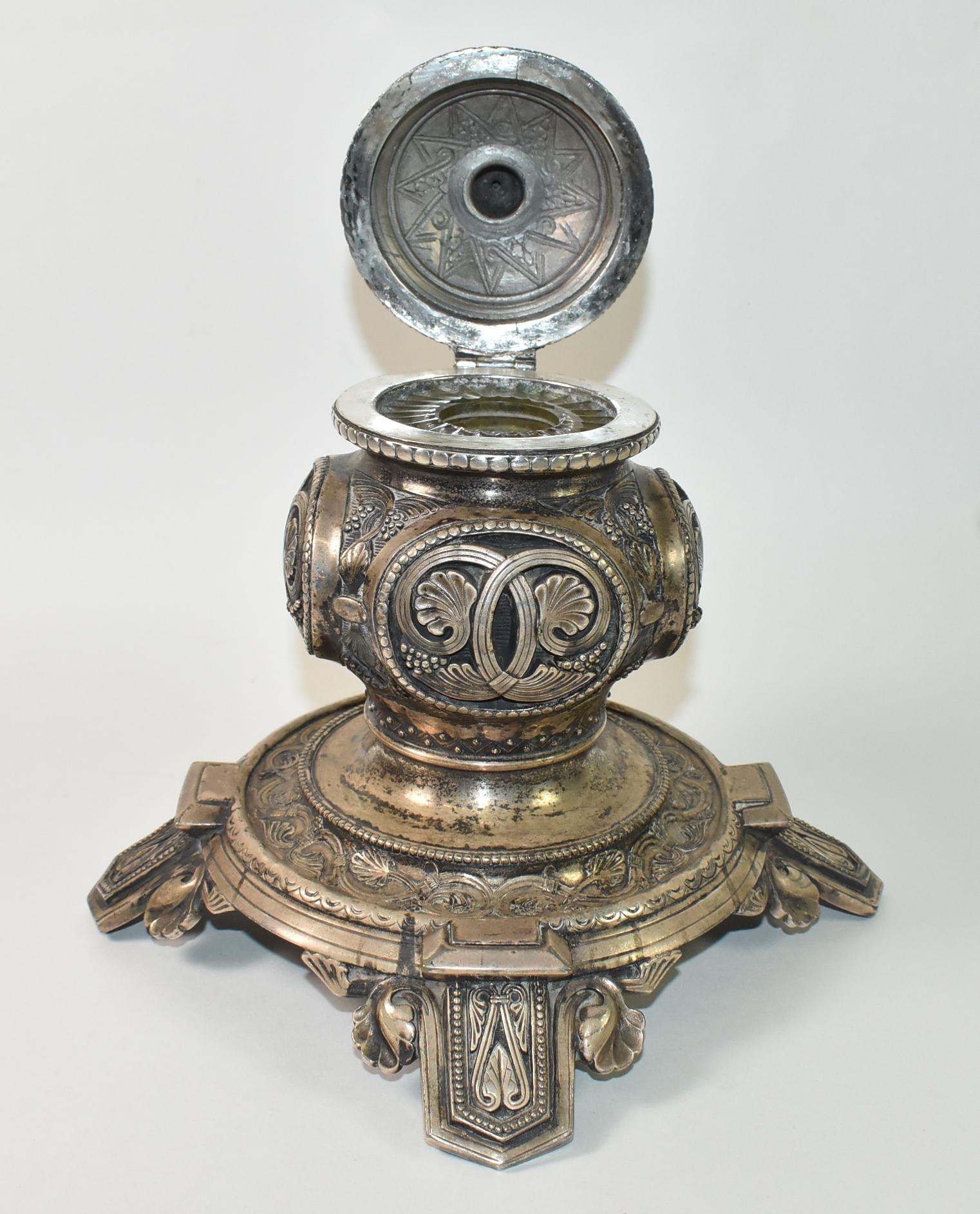 This antique Edwardian inkwell from 1890 is covered in ornate detailing and was made by Elkington. Elkington was established in 1830's - 1963 in Birmingham, England. This inkwell has four decorative feet with leaves and art deco geometric design