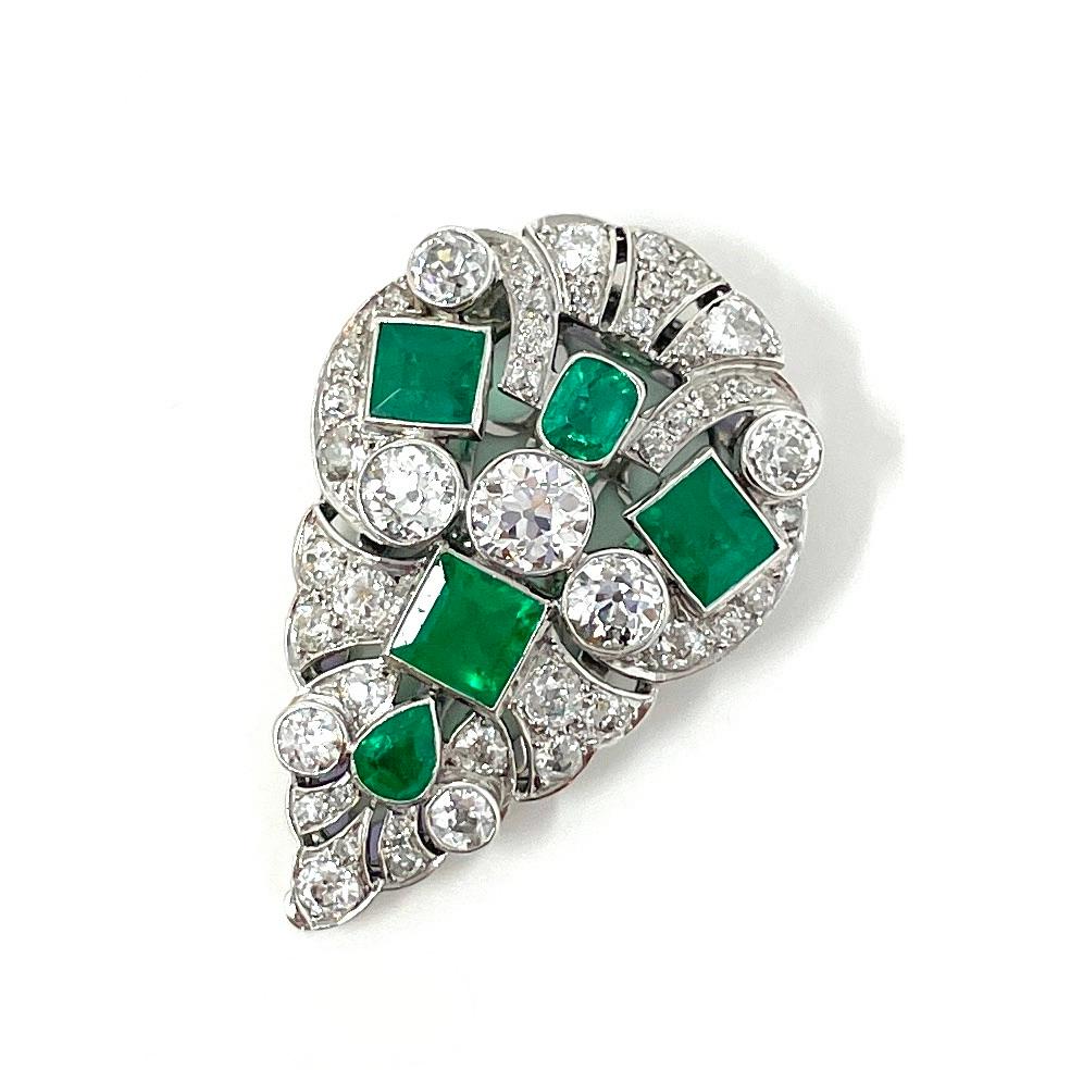 A gorgeous platinum dress clip containing approximately 4 carats total weight of vivid emeralds and approximately 5 carats total weight of old European cut diamonds. The versatility of the dress clip made it a favored style in the early to mid 20th