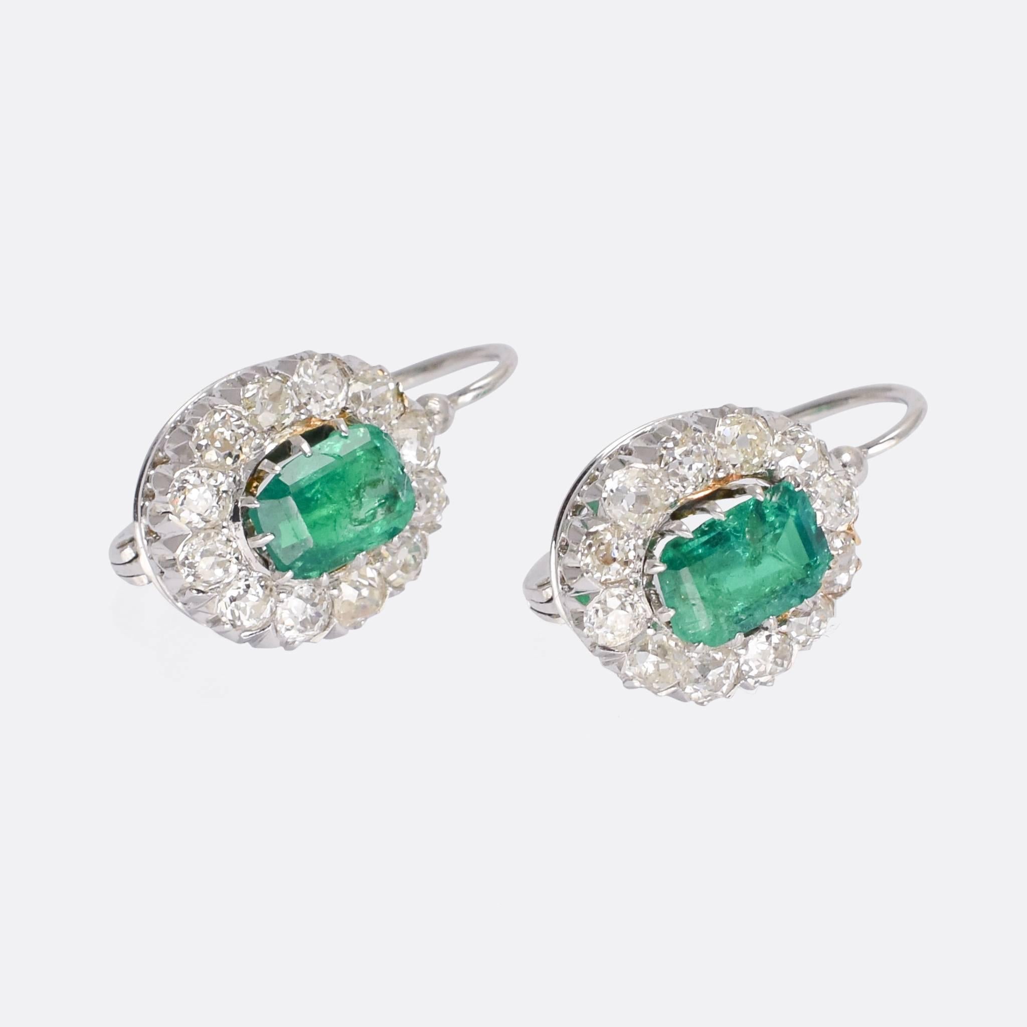 A fine pair of antique cluster earrings set with emeralds and old mine cut diamonds. They have lever backs, that close securely at the top, and the stones rest in fine claw settings; each emerald weighs around 0.75 carats, and each earring is home