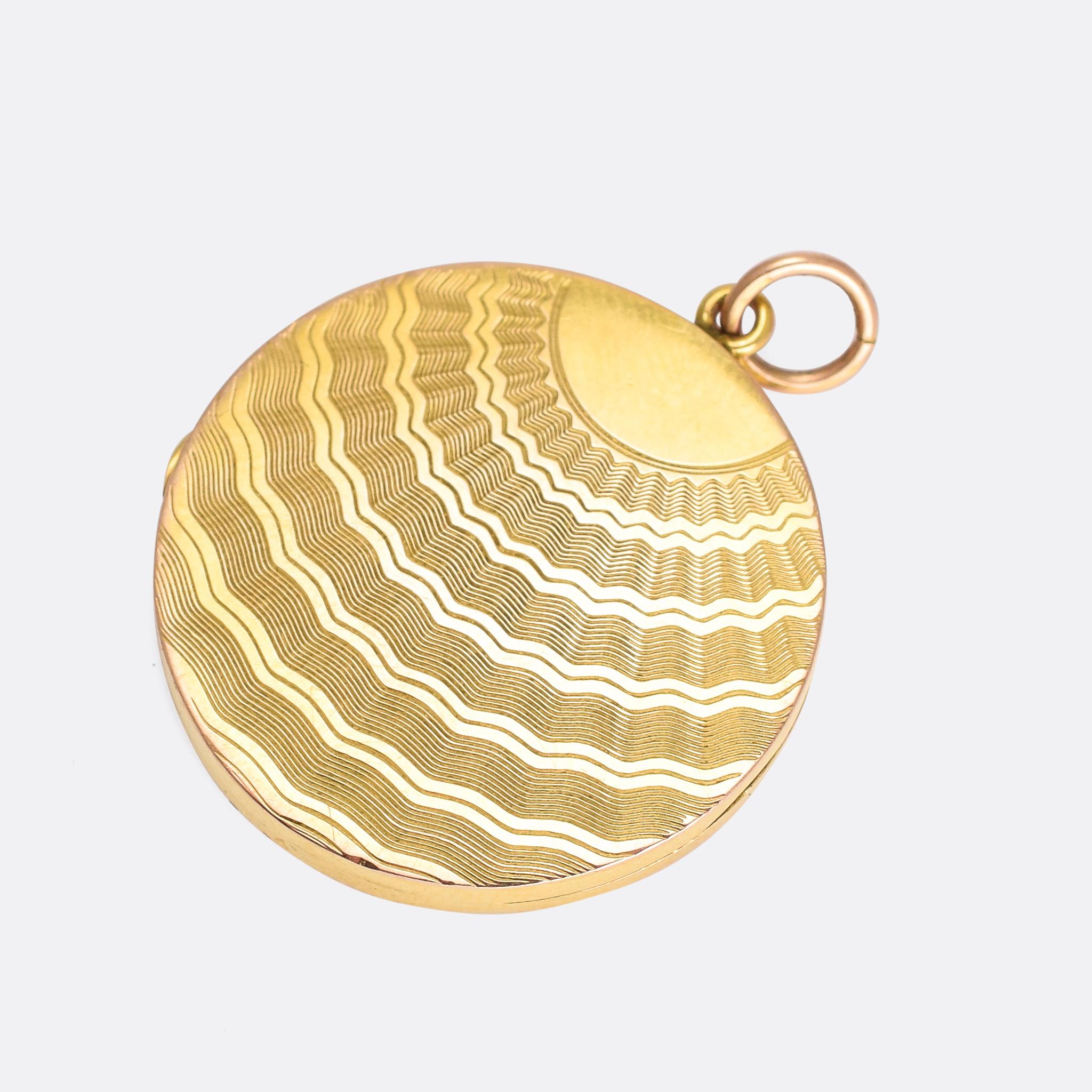 A cool Edwardian period round locket, the gold front and back adorned with a wavy sun rays motif. It catches the light beautifully on account for the fine, engine turned detailing. It dates from c.1915, with a colourised black-and-white photograph