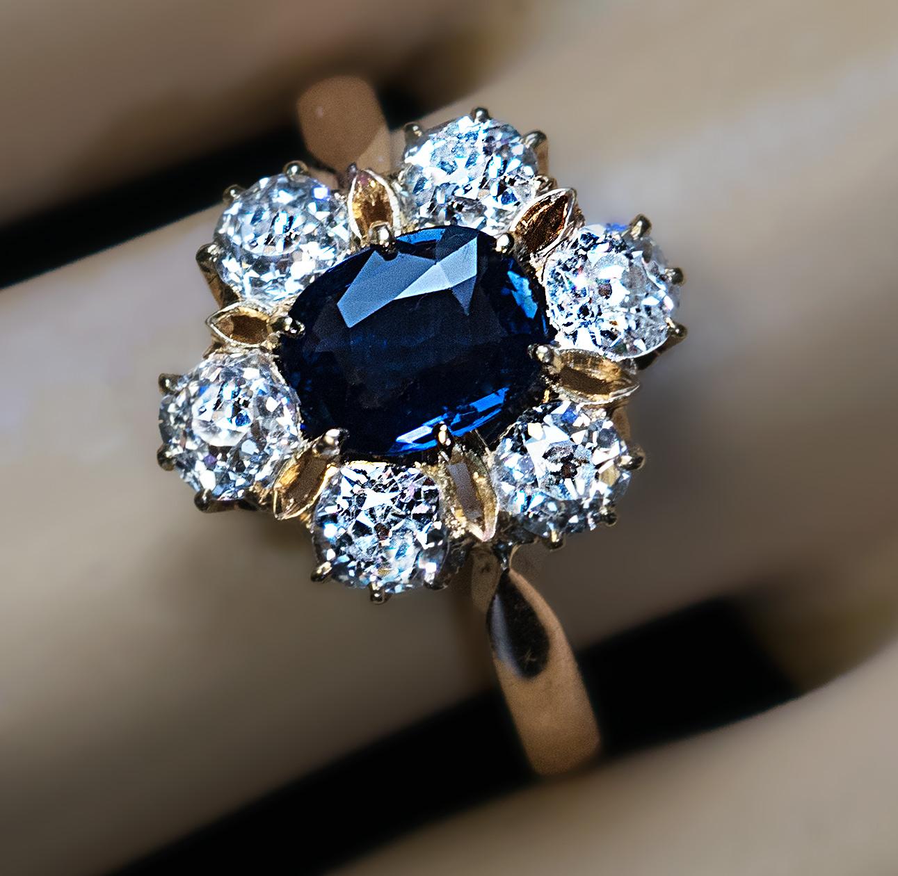 Circa 1910

An antique sapphire and diamond engagement ring is designed as a flowerhead. The ring is crafted in 14K gold and centered with a natural blue sapphire. The center stone is surrounded by six sparkling old European and old cushion cut