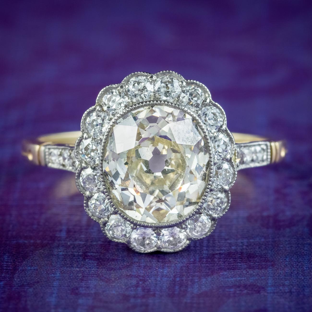 A stunning antique Edwardian daisy cluster ring crowned with a magnificent oval old cut fancy diamond in the centre, haloed by smaller old cut petals around the border and down each shoulder.  

The centre stone has a subtle champagne hue and