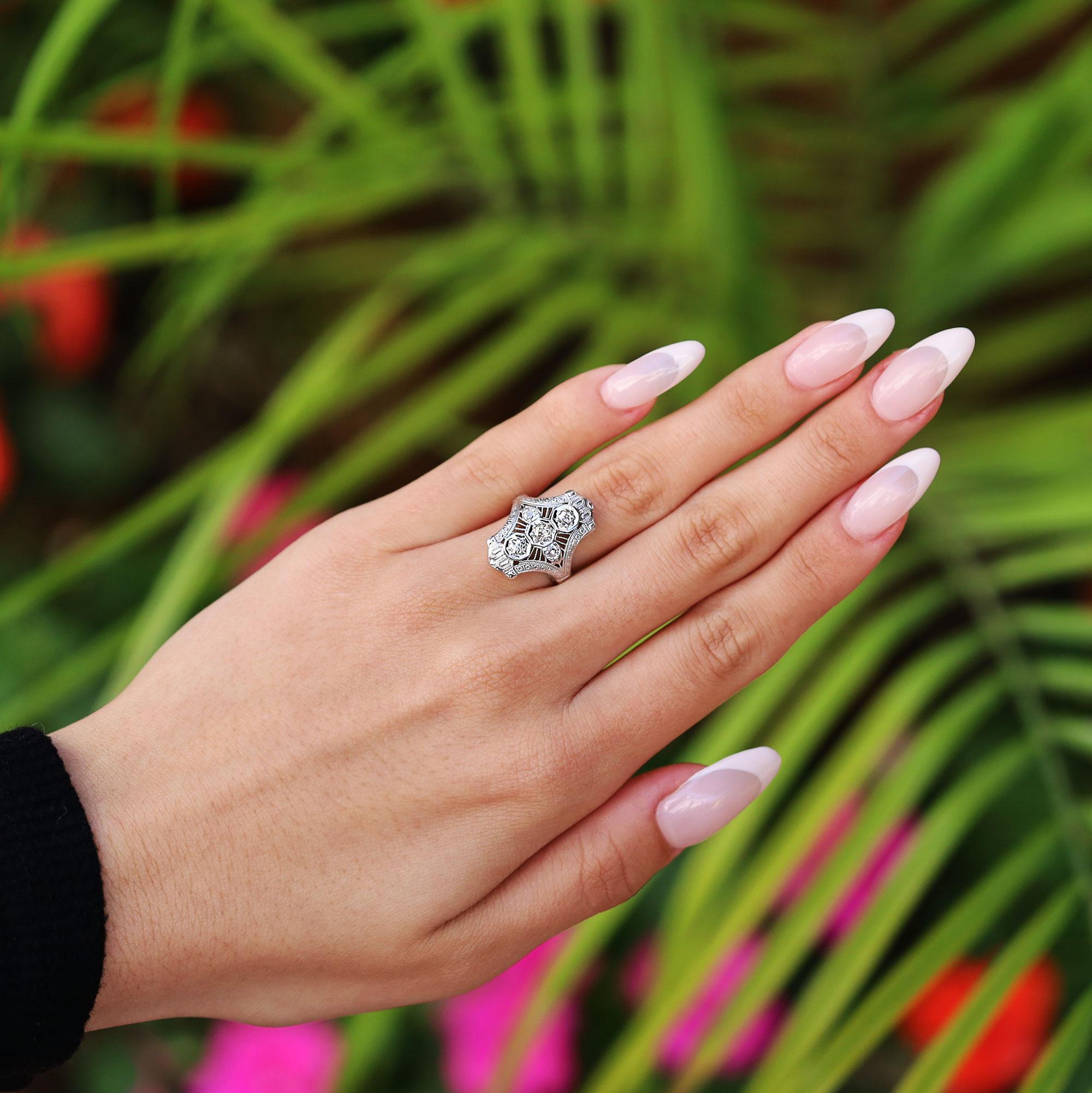 An affordable antique Edwardian era engagement ring. The trinity style is centered with a sparkling warm, white old mine diamond and the surrounding gems create an eye of glinting diamonds. Set in 18k white gold, this antique ring can be enjoyed as