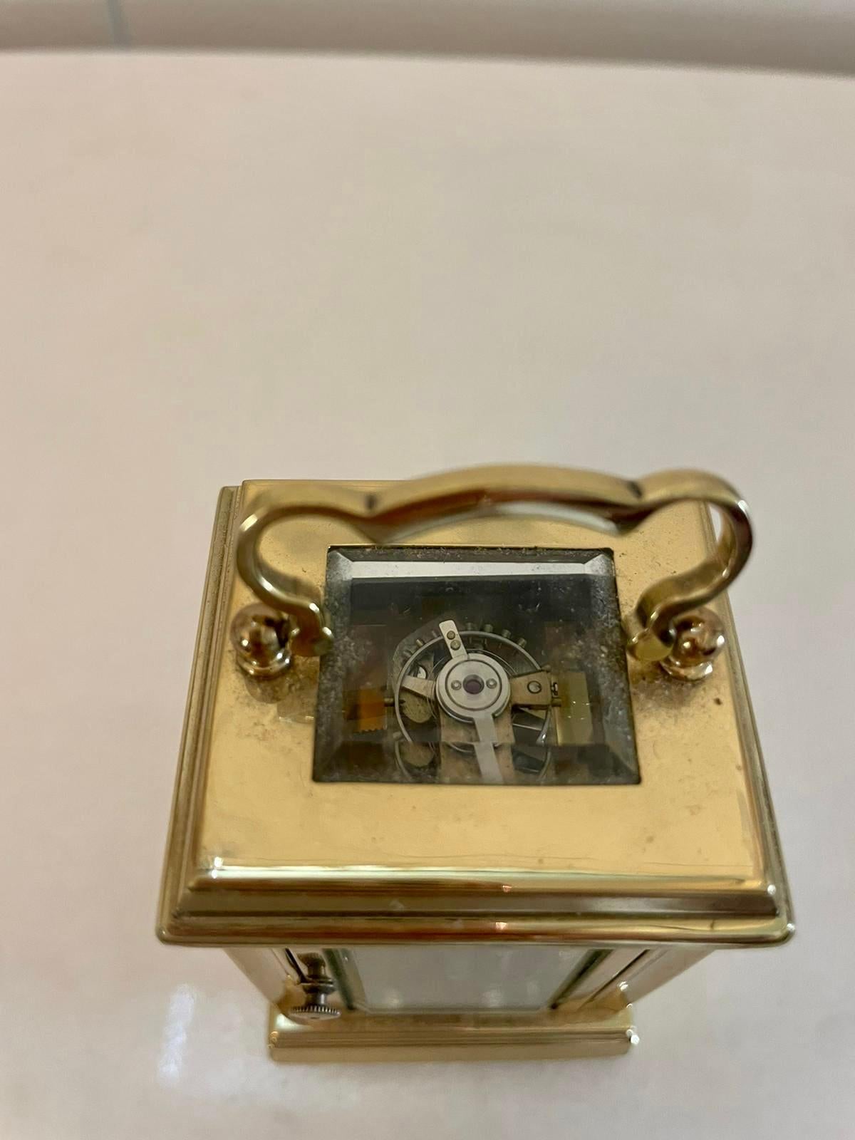 Pendule miniature en laiton de qualité française de l'époque édouardienne, avec un boîtier en laiton de qualité, des coins façonnés et un bord biseauté, des panneaux en verre, une poignée de transport façonnée sur le dessus, un cadran en émail blanc