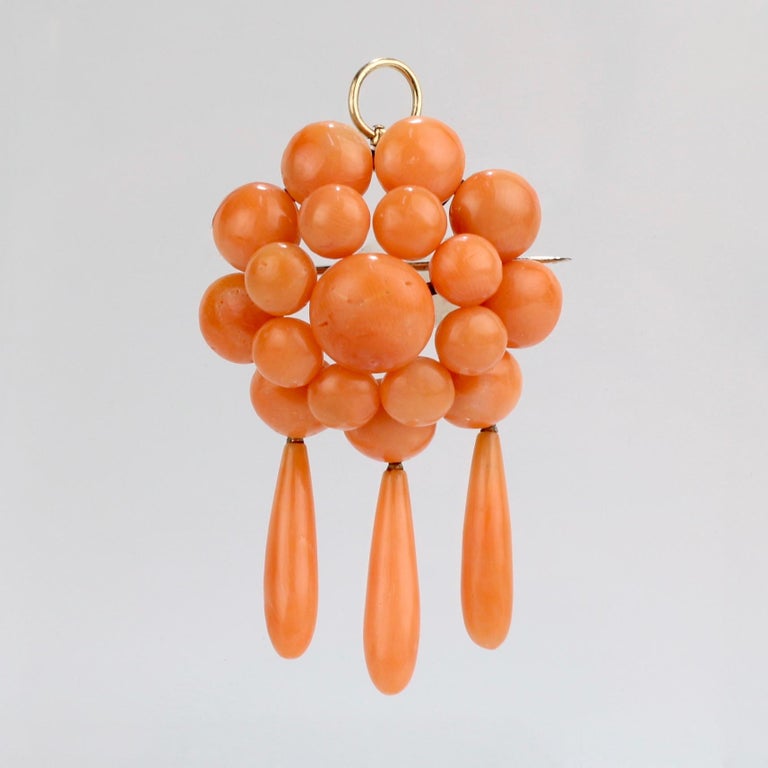 A fine Edwardian coral set comprised of a convertible chandelier pendant/brooch and a pair of chandelier dangle earrings.

Each piece set with multiple salmon-colored coral cabochons and each supporting 3 coral dangle drops. The brooch is fashioned