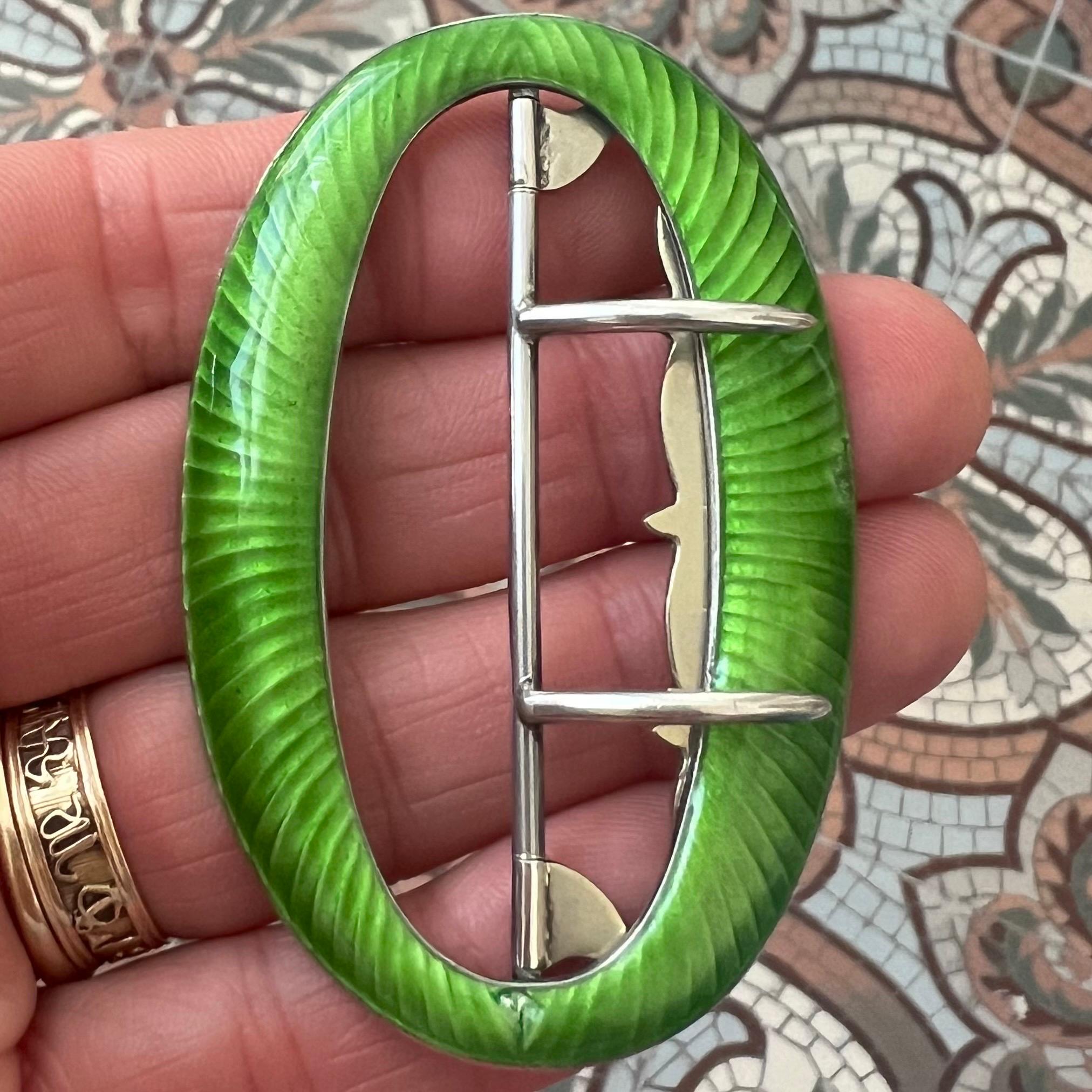 This beautiful antique buckle dates from the Edwardian period, circa 1905, and showcases the refined artistry of early 20th-century enamel work. Crafted in sterling silver, the buckle is beautifully decorated with vibrant green guilloché enamel,