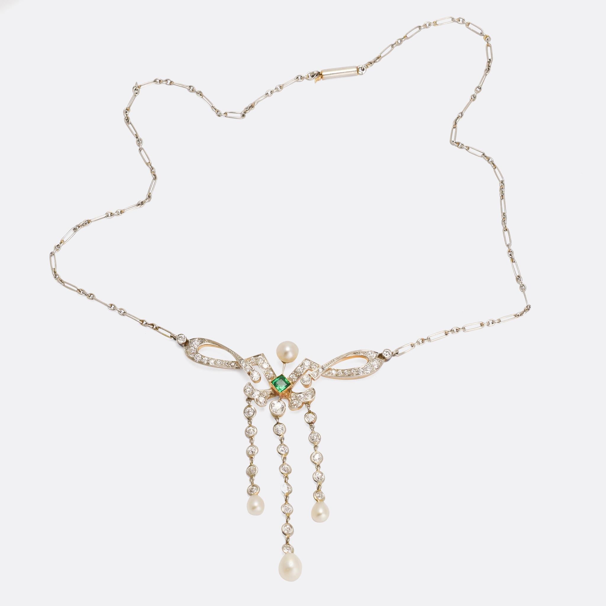 A showstopping example of Edwardian jewellery at its finest. This stunning necklace is made by the esteemed Hancocks & Co. of London, set with over two carats of old cut diamonds, four natural pearls, and a vibrant emerald centrepiece it's both