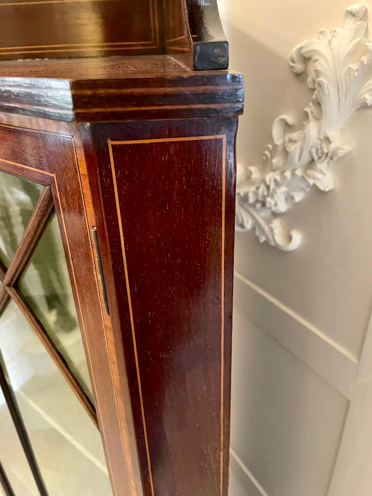 Antique Edwardian inlaid mahogany corner display cabinet having a mahogany gallery top with satinwood inlay, single inlaid mahogany astragal glazed door opening to reveal two shelves standing on shaped spade legs with satinwood stringing

A