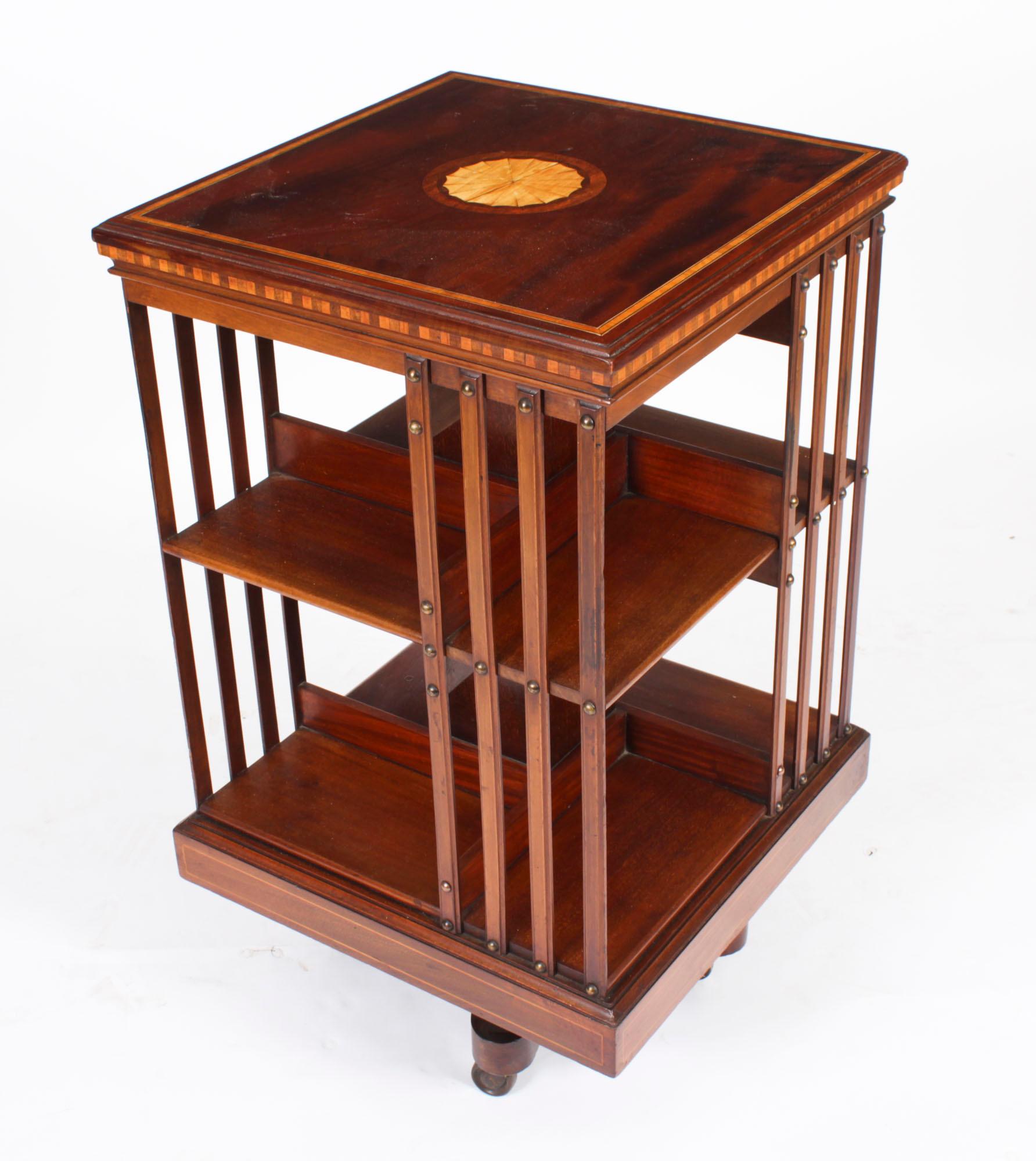 This is an exquisite antique Edwardian marquetry inlaid flame mahogany revolving bookcase, attributed to the renowned Victorian retailer and manufacturer Maple & Co., circa 1900 in date.

It is made of mahogany  and revolves on a solid cast iron