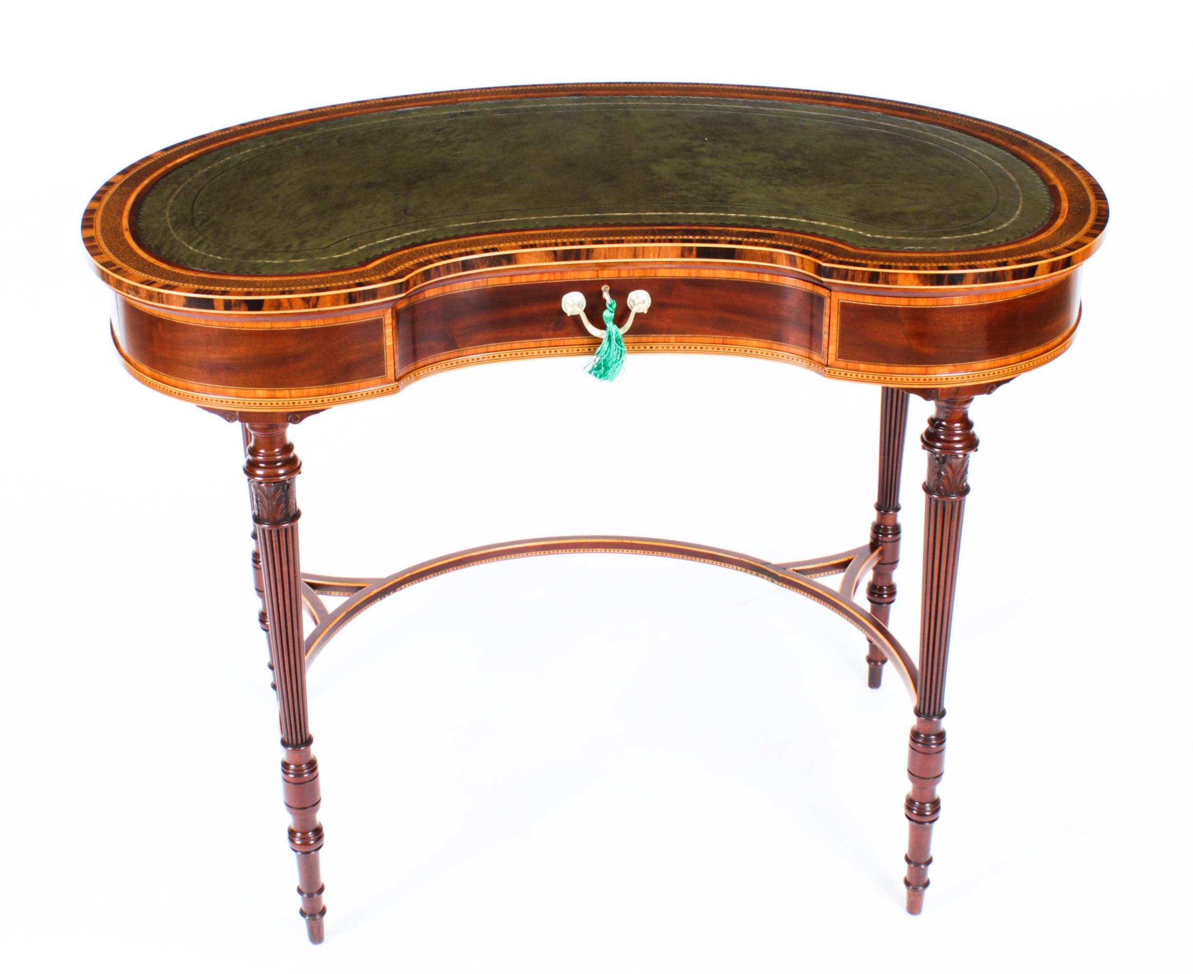 This is a fabulous quality antique Edwardian kidney shaped mahogany writing table by Maple & Co, circa 1890 in date. 
 
The shaped top is cross banded in various exotic specimen woods with an inset gold tooled green leather writing surface. The