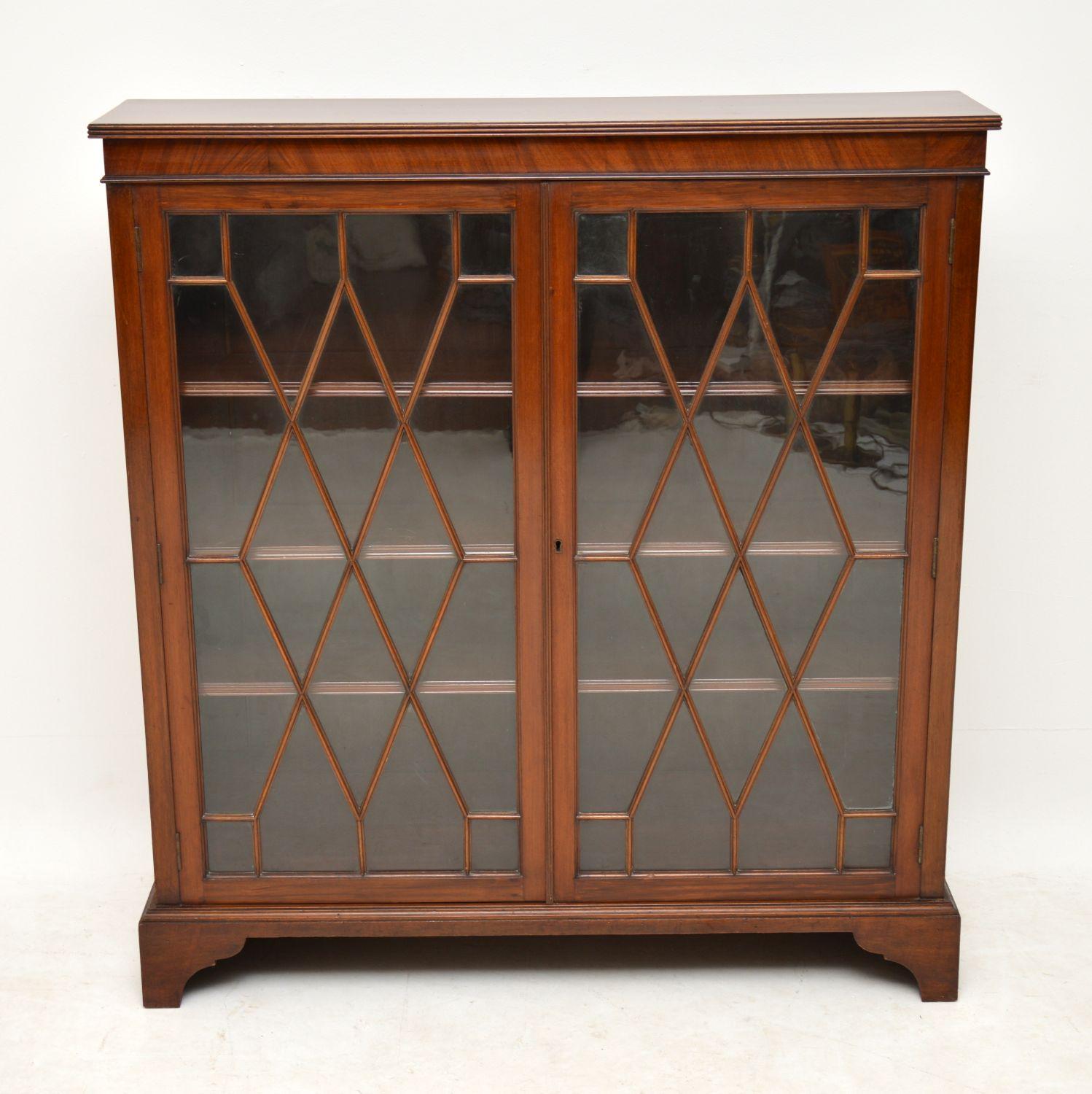 Fine quality antique Edwardian mahogany bookcase in excellent condition and dating to circa 1910 period. It has a reeded top edge, astral glazed doors, adjustable shelves and sits on bracket feet. This is a very elegant bookcase and slim from back