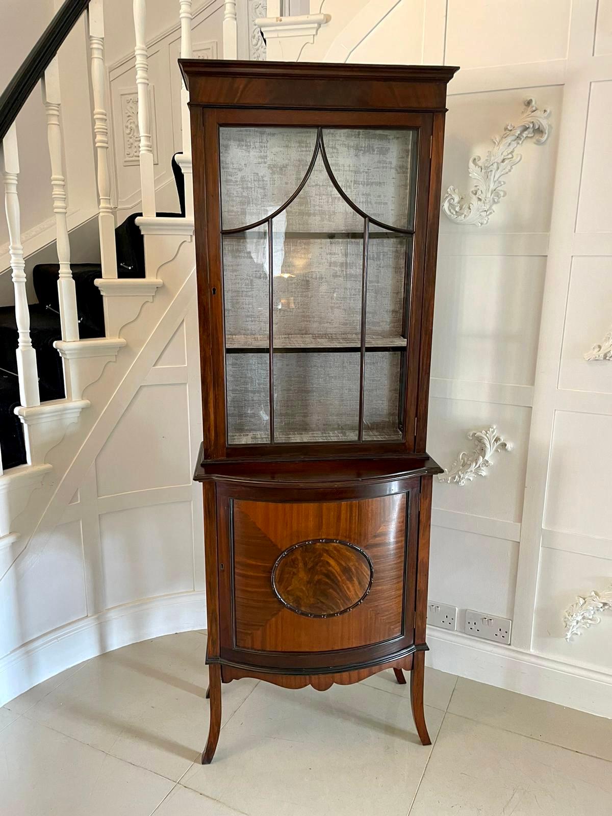 Antique Edwardian mahogany display cabinet having an astragal glazed door to the top section with a fitted interior and two shelves. The base has a bow front door with a lovely carved panel standing on four out swept legs 

A fabulous piece