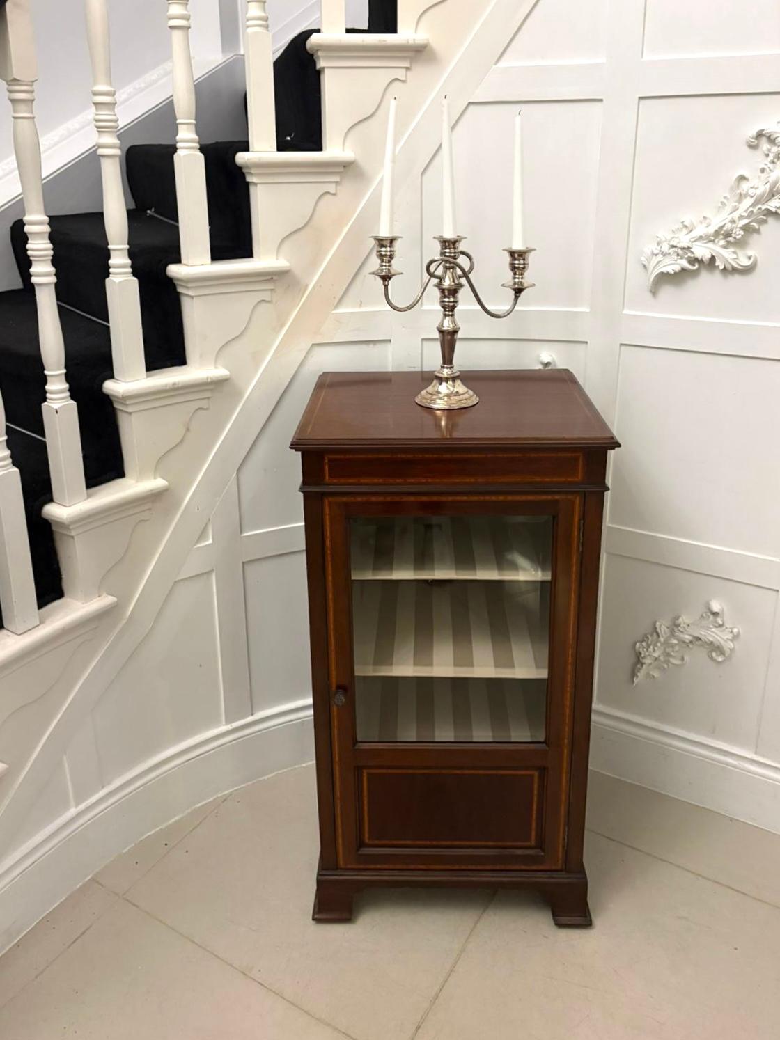 Un'elegante vetrina edoardiana in mogano intarsiato di pregiata fattura e dal fascino senza tempo. Il mobile presenta una cassa in mogano splendidamente lucidata, arricchita da un'incorniciatura in legno satinato e da dettagli a fasce incrociate che