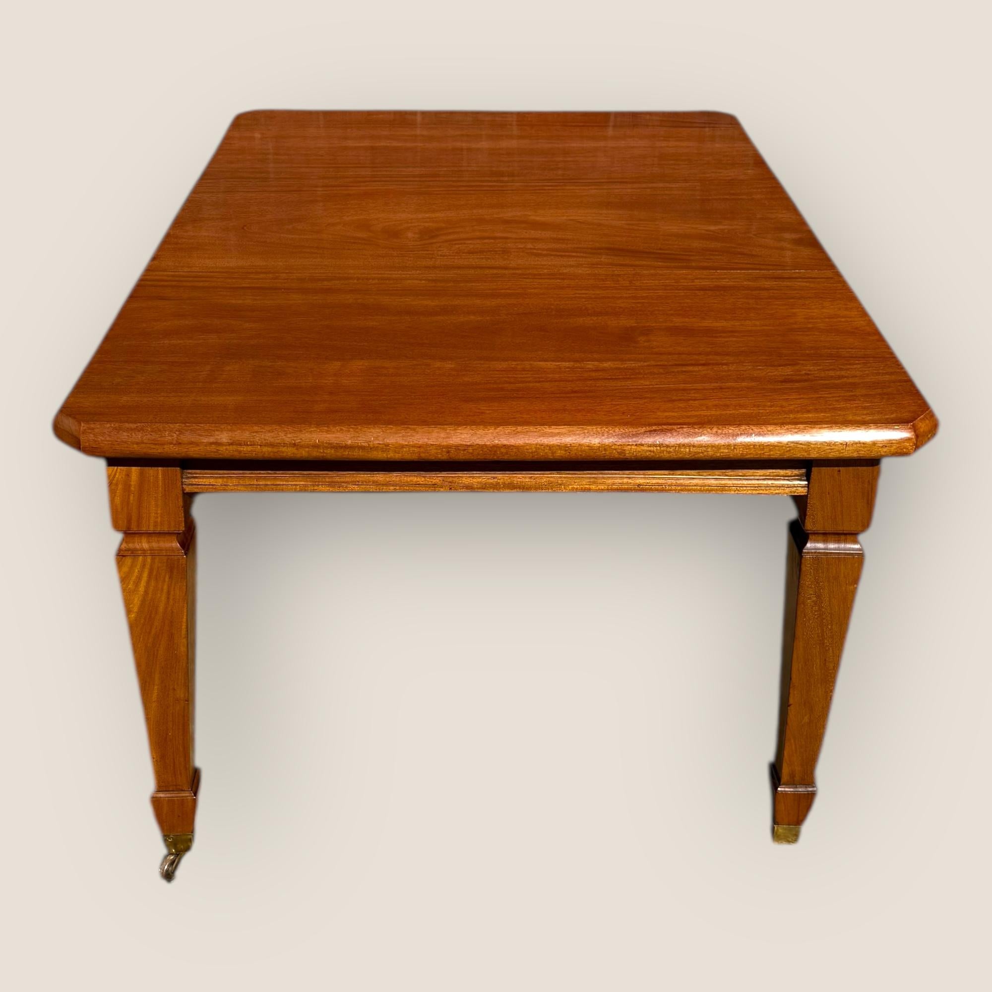 Hier haben wir einen antiken edwardianischen (1901-1910) Mahagoni-Auszieh-Esstisch mit einer zusätzlichen Platte. Er steht auf vier geraden, konisch zulaufenden Beinen mit Messingrollen und ermöglicht so eine leichte Mobilität und ein sanftes