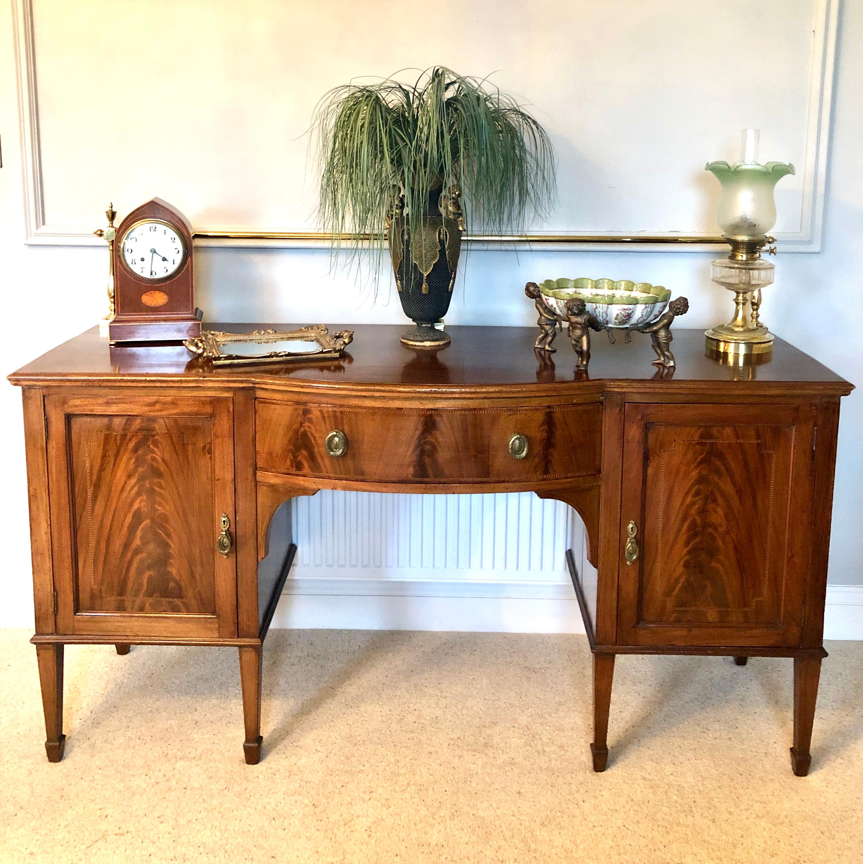 Antique Edwardian mahogany inlaid sideboard by Hamptons and Sons, Pall Mall, London having the original brass rail to the back and a superior quality inlaid mahogany bow front top, bow front drawer to the centre with attractive original brass